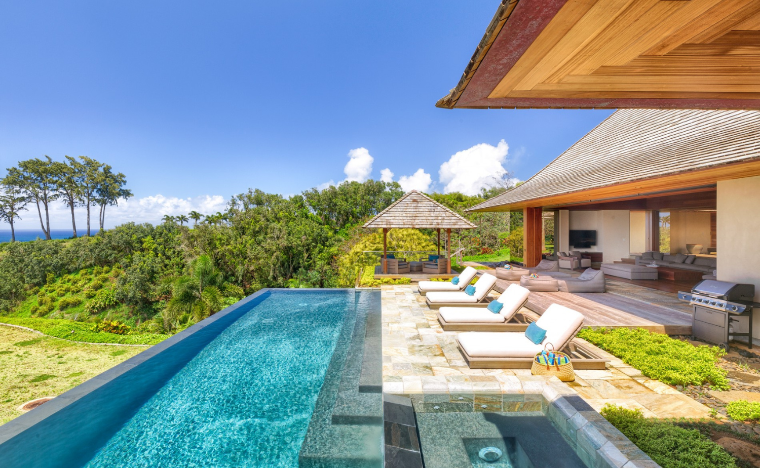 A private tropical villa with an infinity pool overlooking lush greenery and the Pacific Ocean.