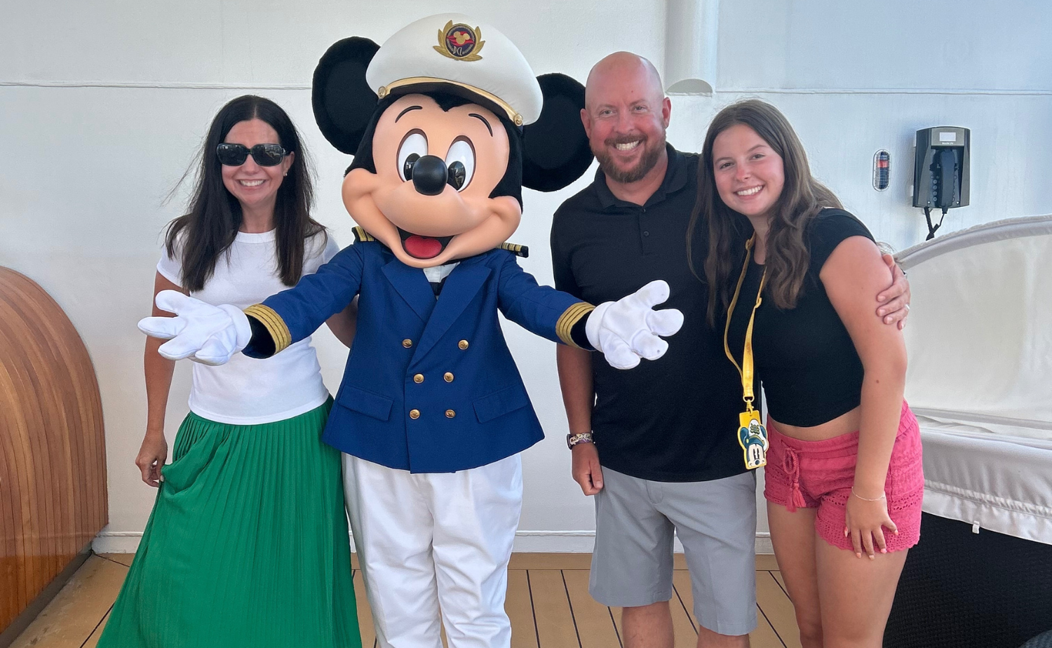Family posing with Captain Mickey on deck during their Disney Cruise