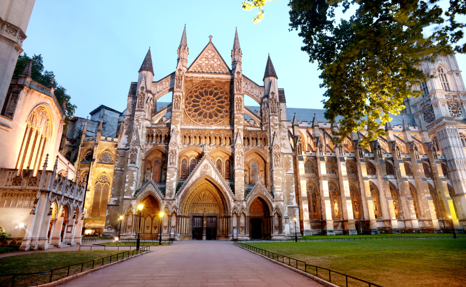 Evening view of Westminster Abbey illuminated against the sky, highlighting its Gothic architecture.