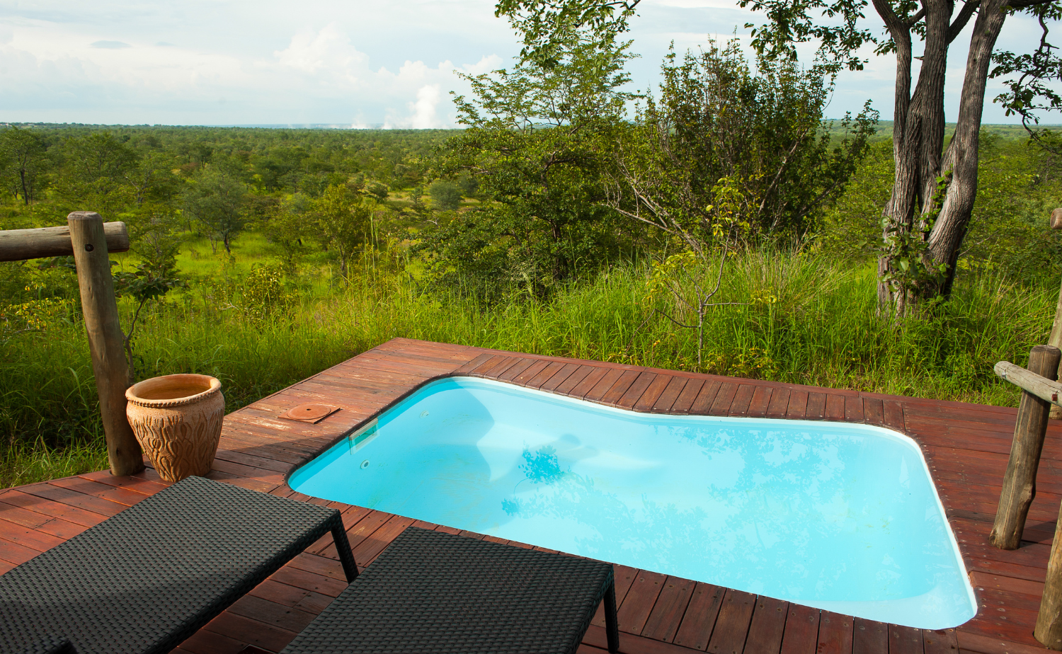 Private plunge pool and wooden deck overlooking the African bush at a luxury safari lodge.