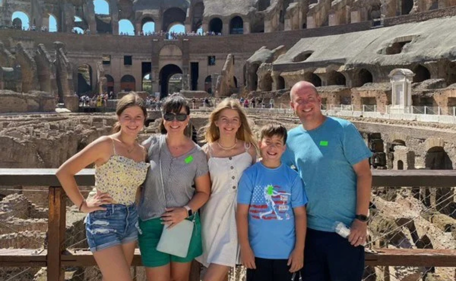A family smiling together inside the Colosseum with ancient stone arches in the background.