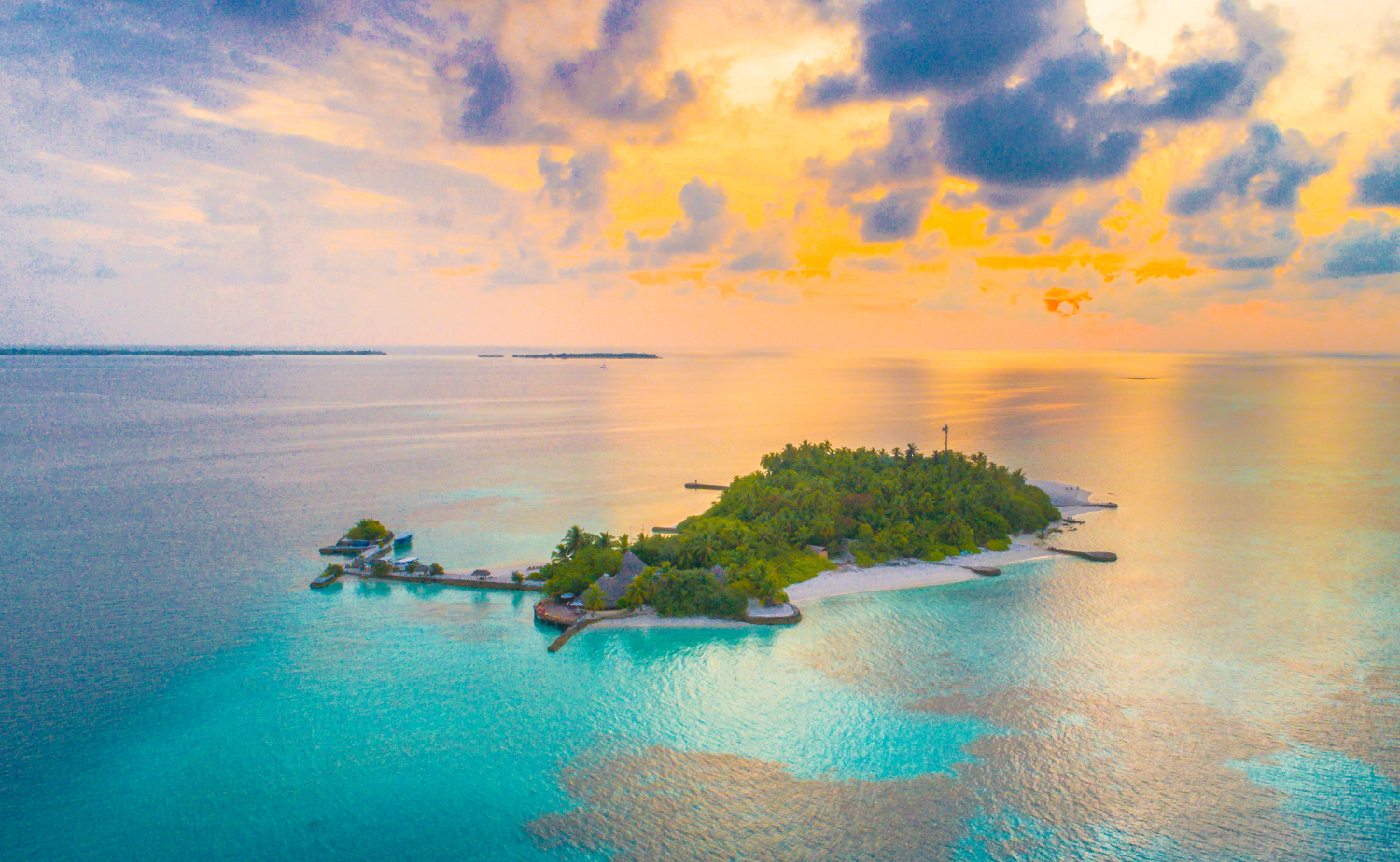 Aerial view of a small tropical Caribbean island surrounded by turquoise water at sunset.