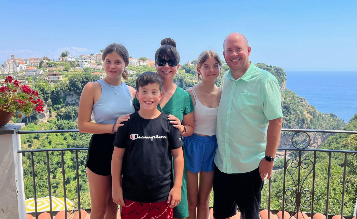 A smiling family posing on a scenic terrace in Amalfi, Italy.