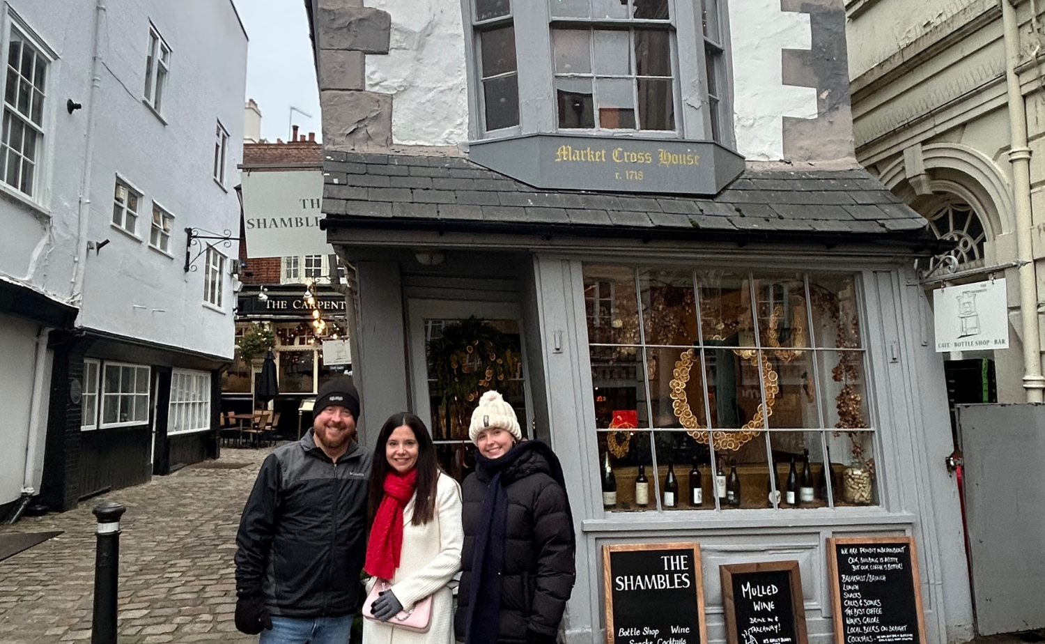 Family standing on the cobblestone street of The Shambles in York, surrounded by historic timber-framed buildings.