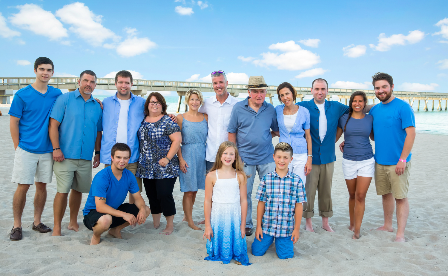 A large extended family posing together on the beach during a multi-generational family vacation.