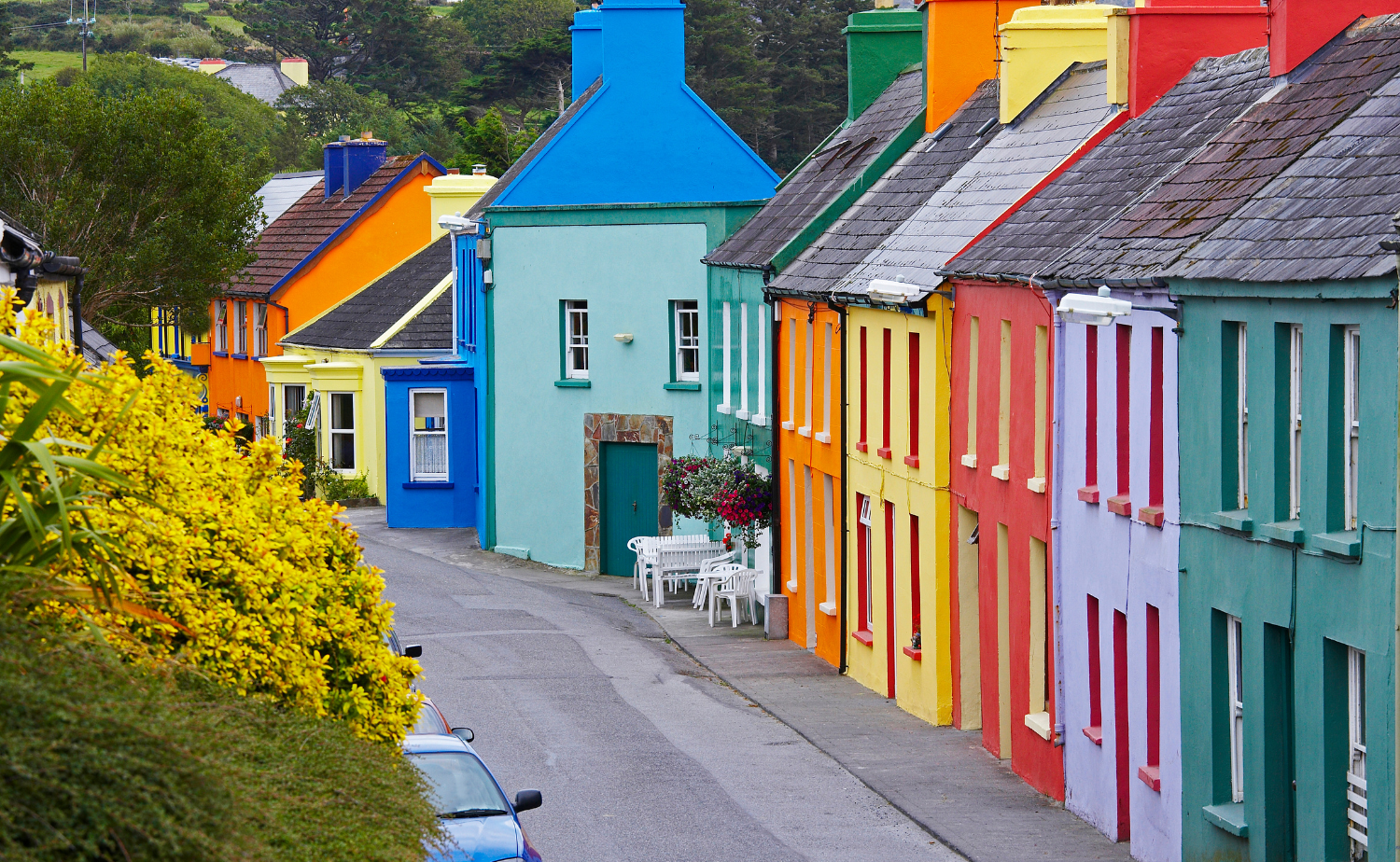 A row of brightly painted houses lining a quiet street in a small Irish town.
