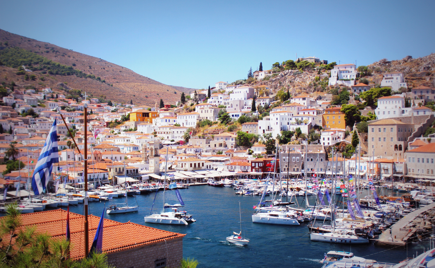 Sailboats and traditional hillside homes surrounding the picturesque harbor of Hydra, Greece