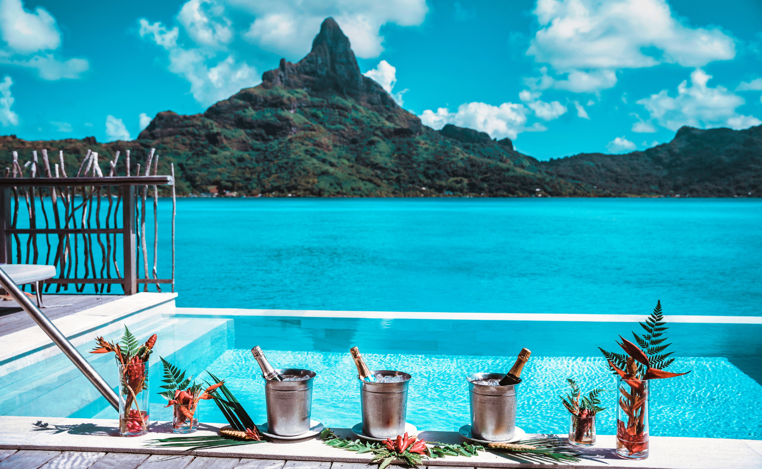 An infinity pool overlooking turquoise water and a dramatic mountain peak in Bora Bora with champagne on ice.