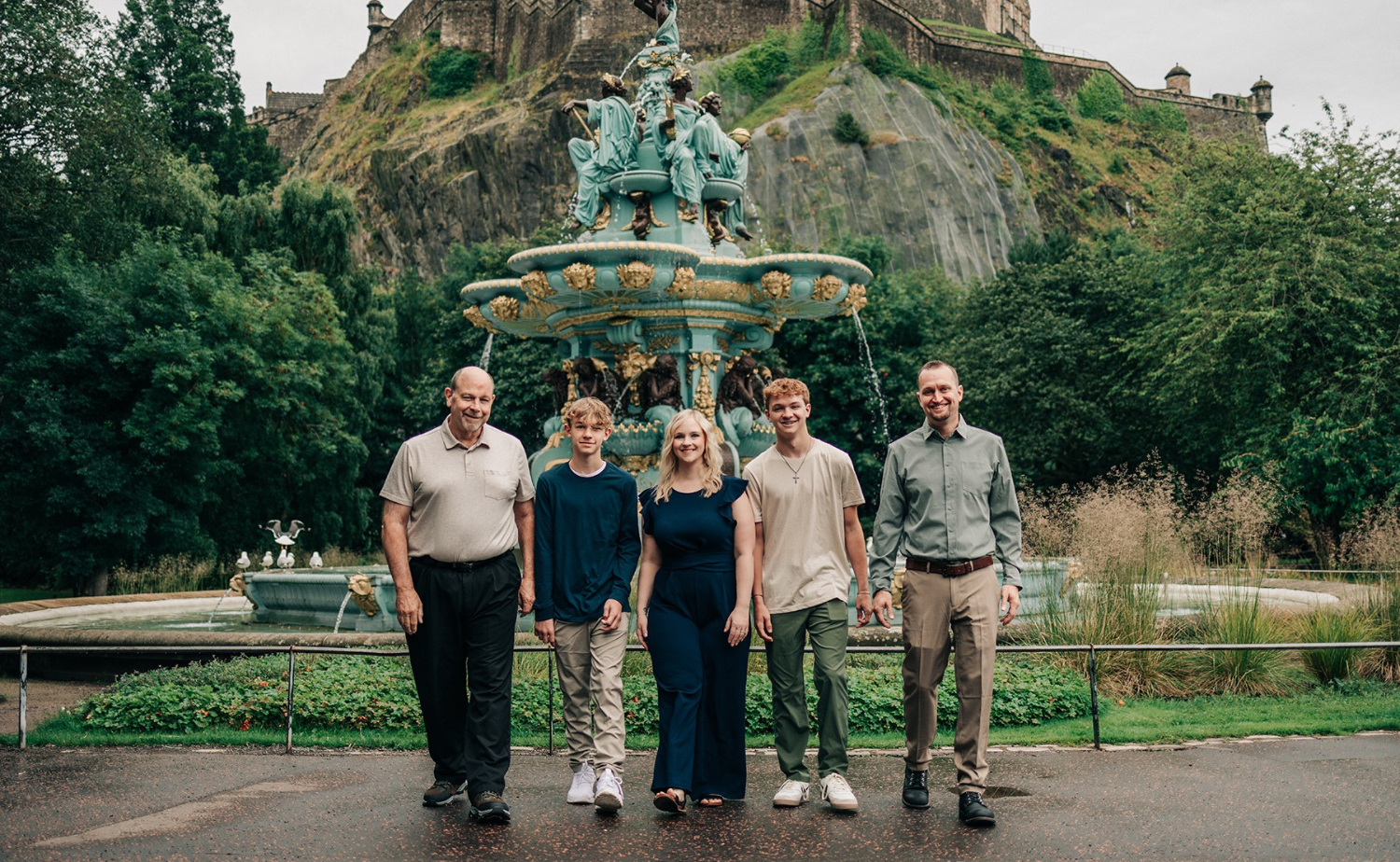 A multigenerational family stands in front of a historic fountain in Edinburgh.