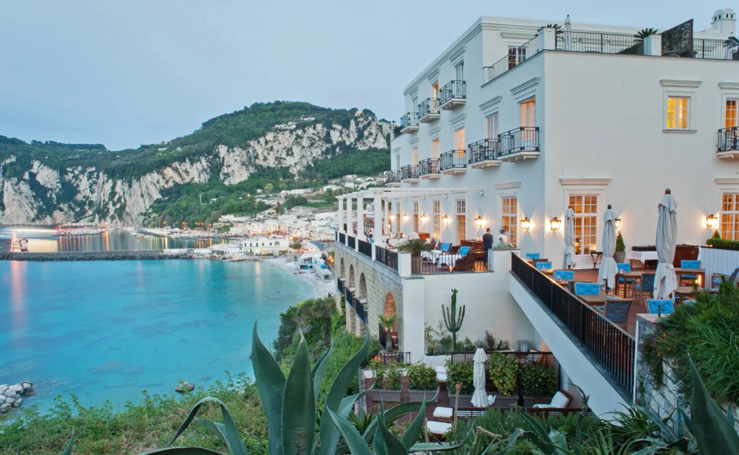 Luxury coastal hotel terrace at J.K. Place Capri overlooking turquoise water and dramatic cliffs along the Italian coastline.