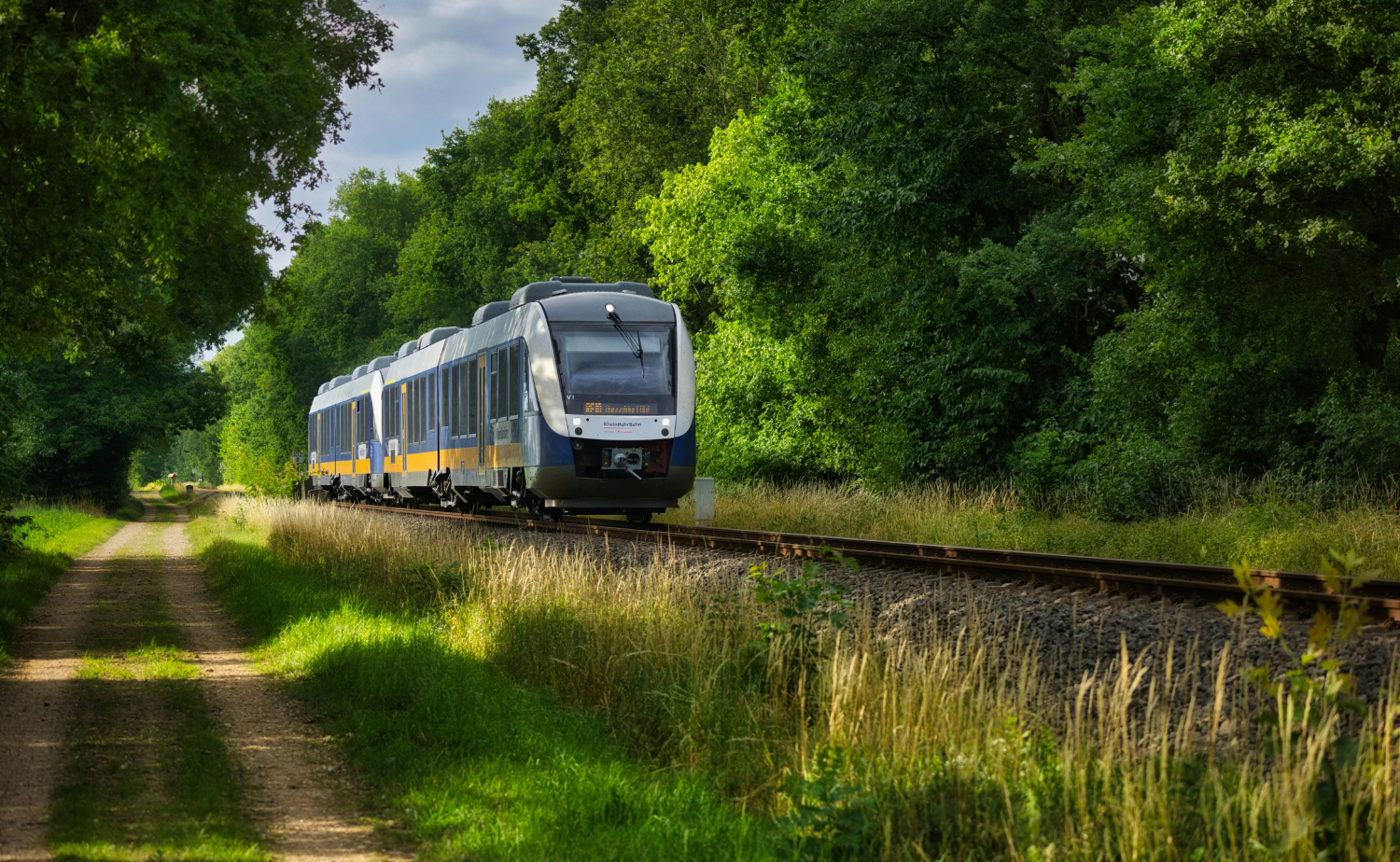 A passenger train traveling through lush green countryside in Ireland on a sunny day.