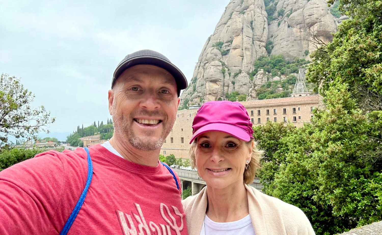 A couple smiling in front of Montserrat mountain and monastery in Spain.