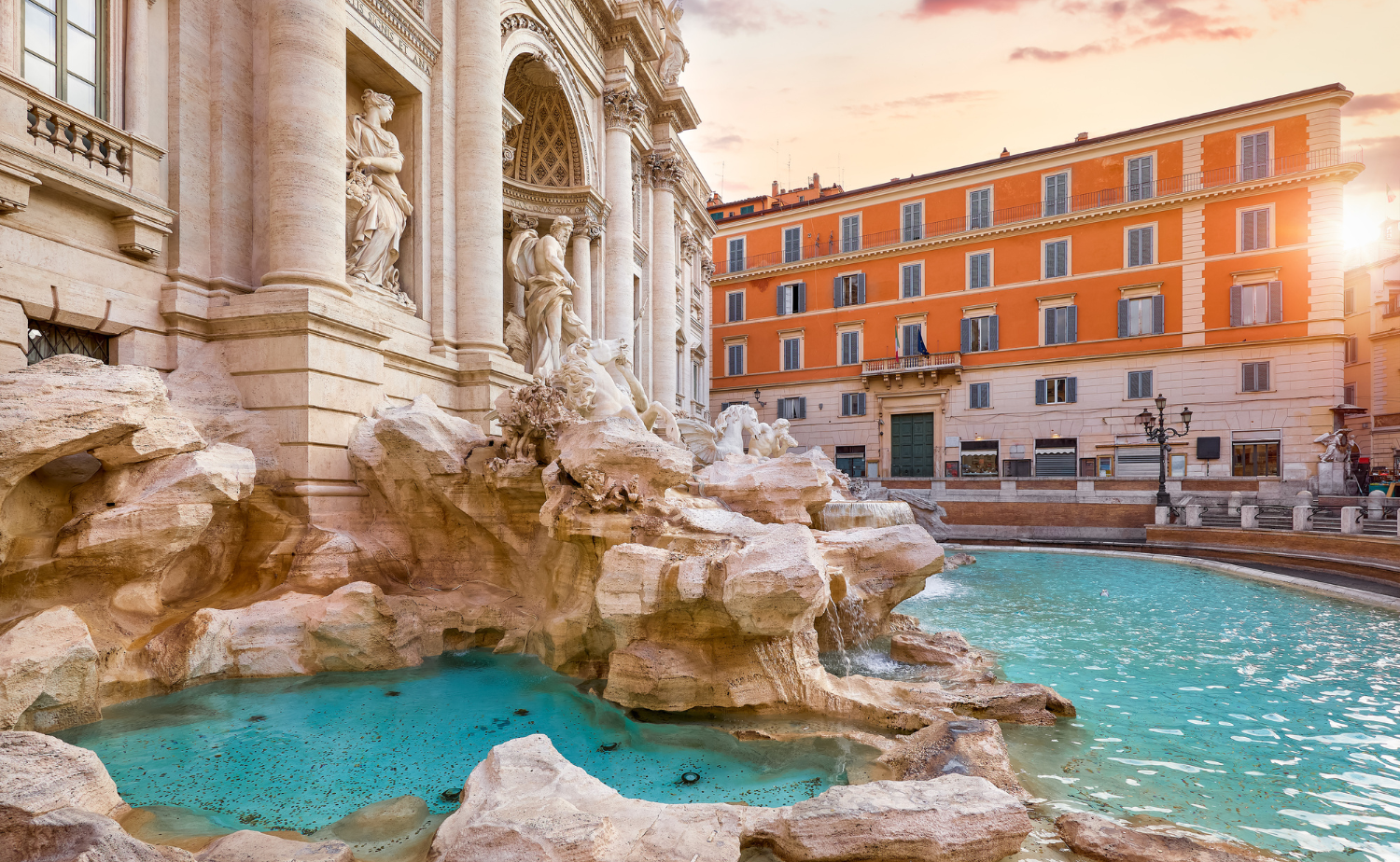The Trevi Fountain in Rome with turquoise water and detailed sculptures illuminated by soft morning light.