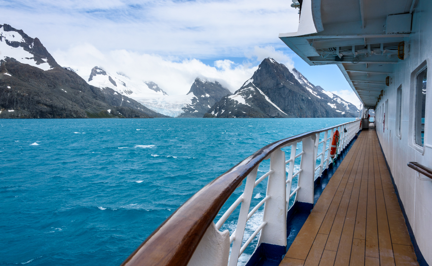 View from an expedition cruise ship deck toward snow-covered mountains and glaciers