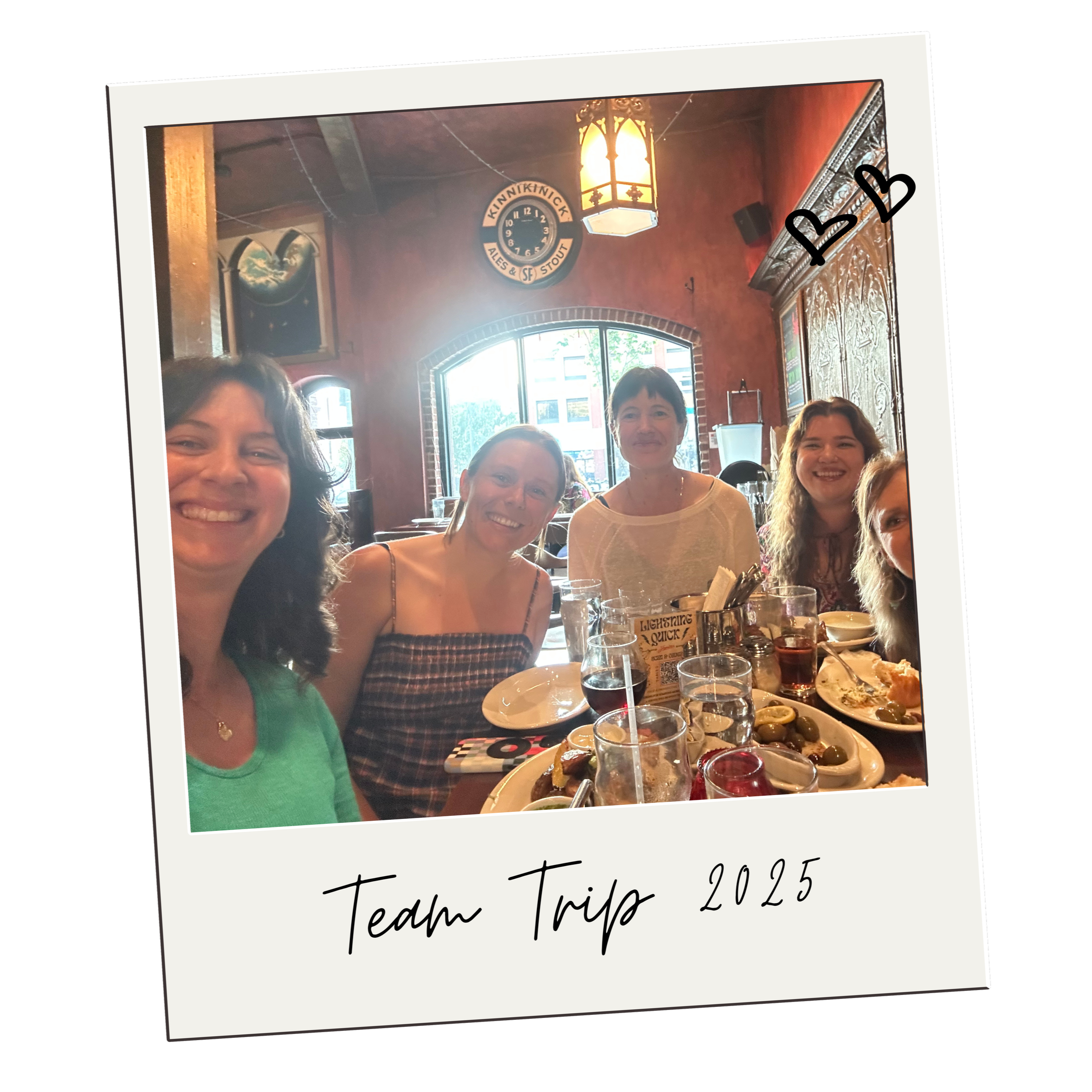 A picture of five women on the Brilliant Births team out to dinner in a cozy restaurant, looking happy. Image is stylized to look like a polaroid picture, and in handwriting on the white strip below the picture it says Team Trip 2025.