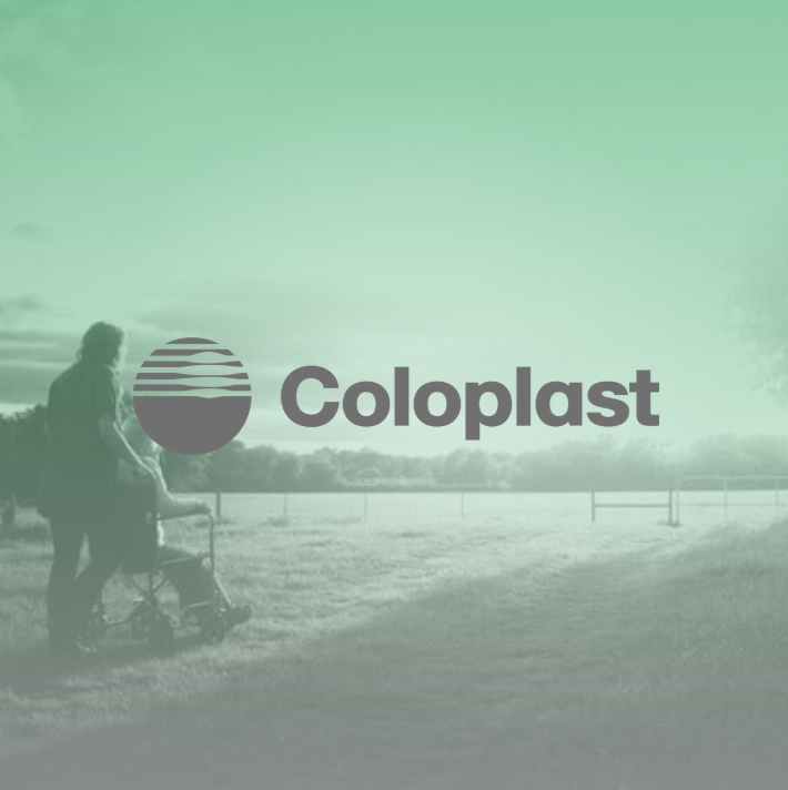 Logo for Coloplast over en sort og hvid foto af en person med barnevogn, der går langs en sti i et åbent landskab.