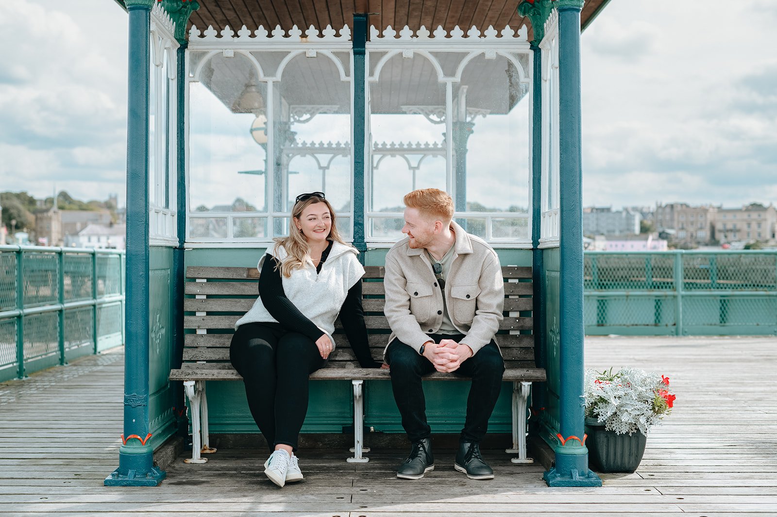 A couple smiling at each other on Clevedon Pier during the engagement session by Victoria Beddoes