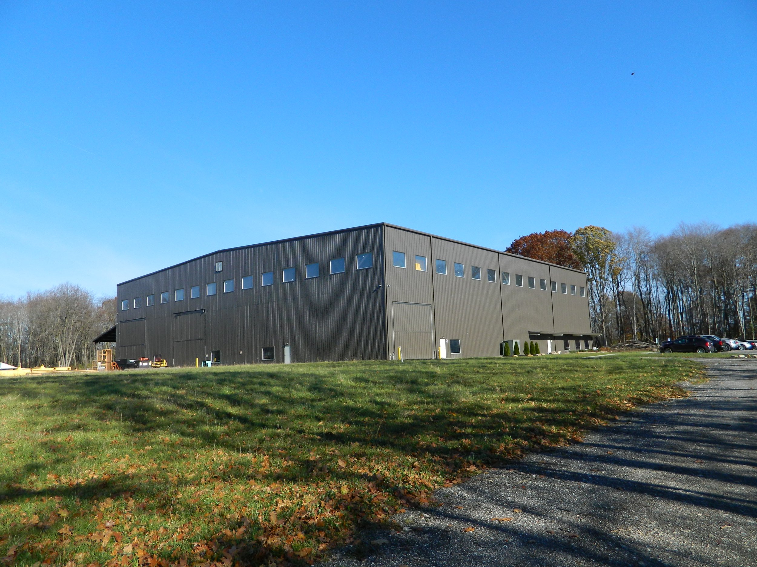 Exterior of KDA Phase 1 heavy manufacturing facility in Norton, Ohio, showing the high-bay industrial building, upper daylighting windows, and landscaped grounds.