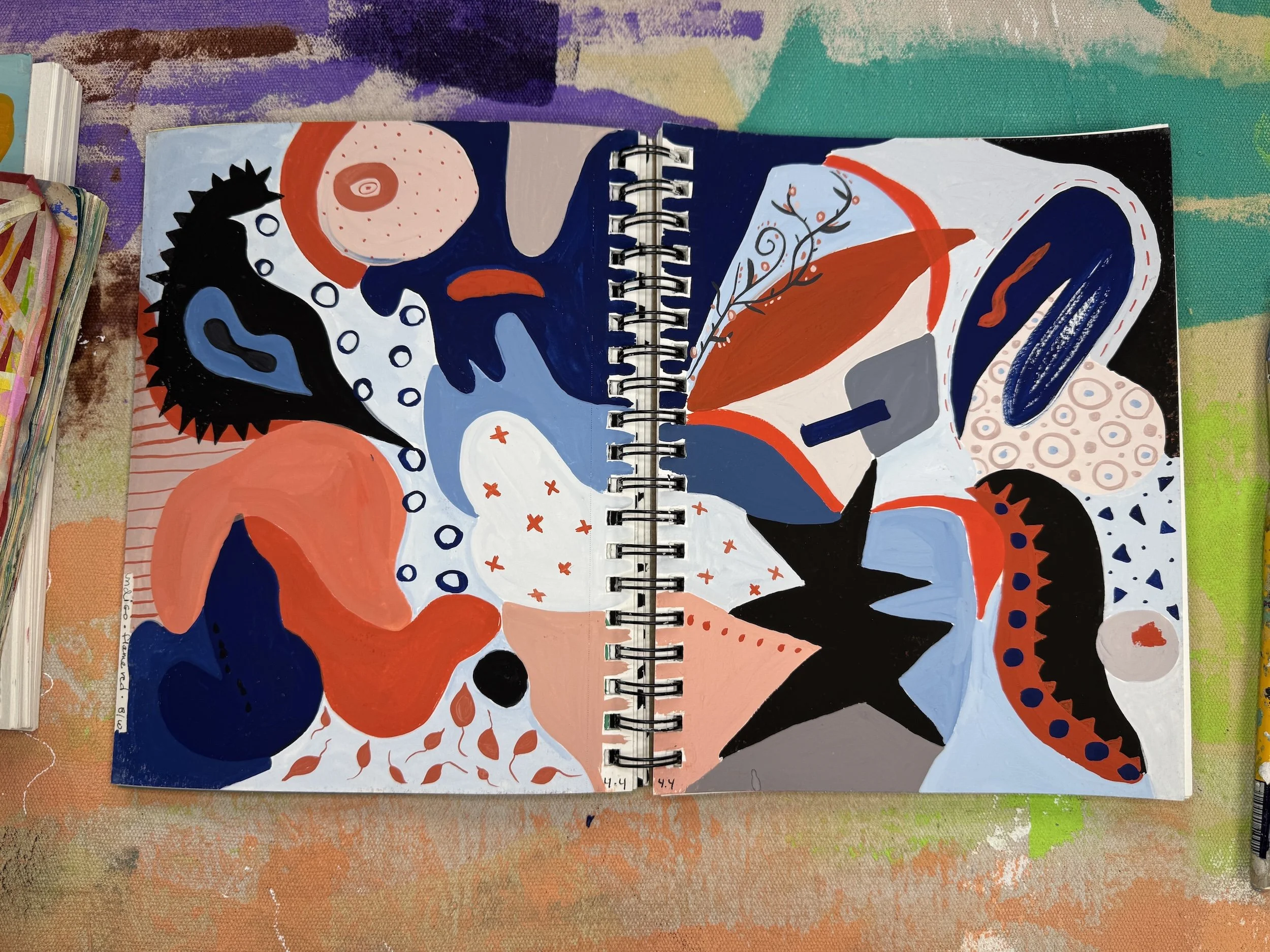 Abstract colorful painting featuring various shapes and patterns, including star, leaf, and eye-like motifs, with a color palette of black, blue, red, white, orange, and shades of gray.