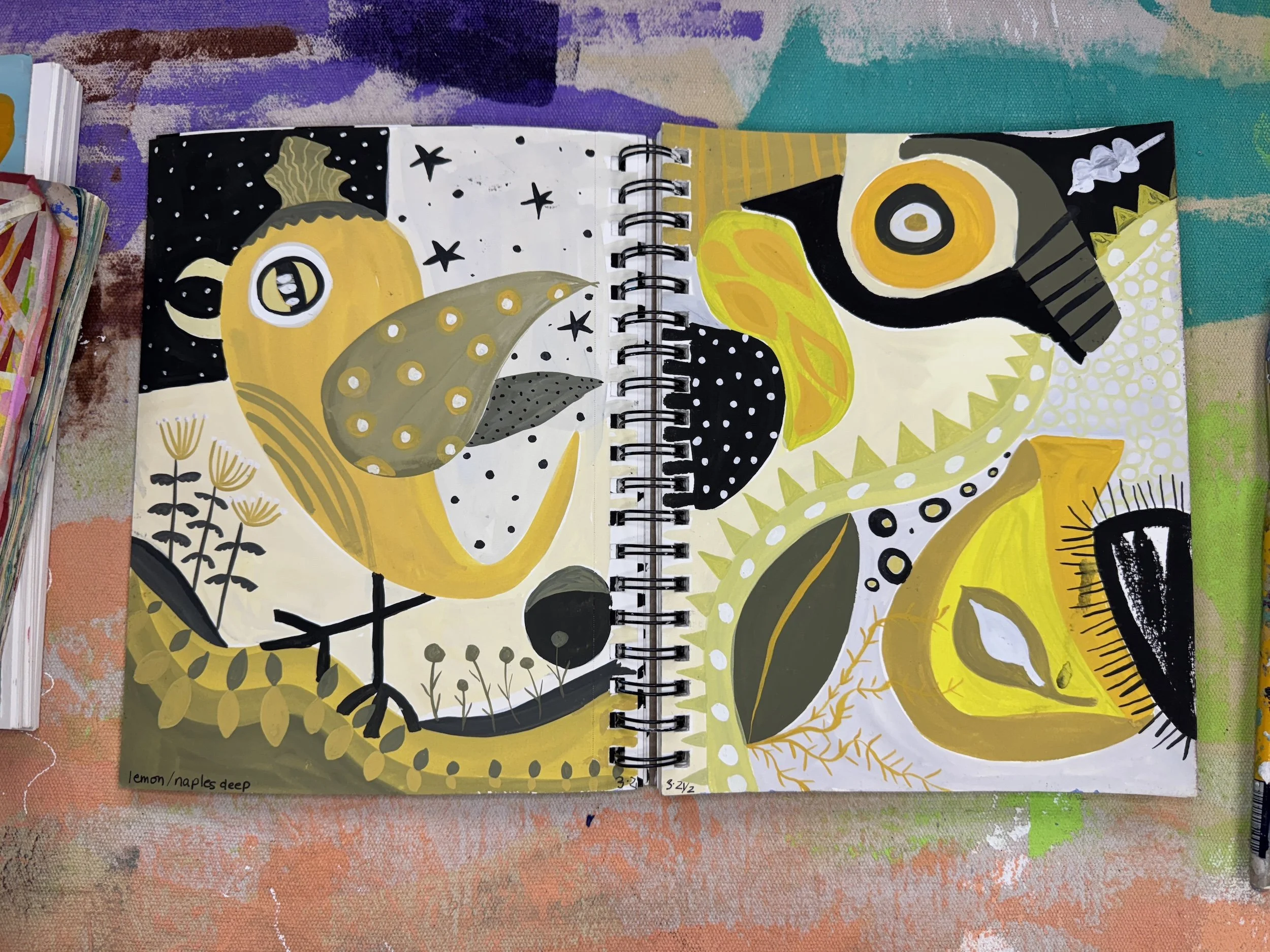 Open sketchbook with abstract, colorful illustrations of birds and flowers using black, white, yellow, and grey tones.