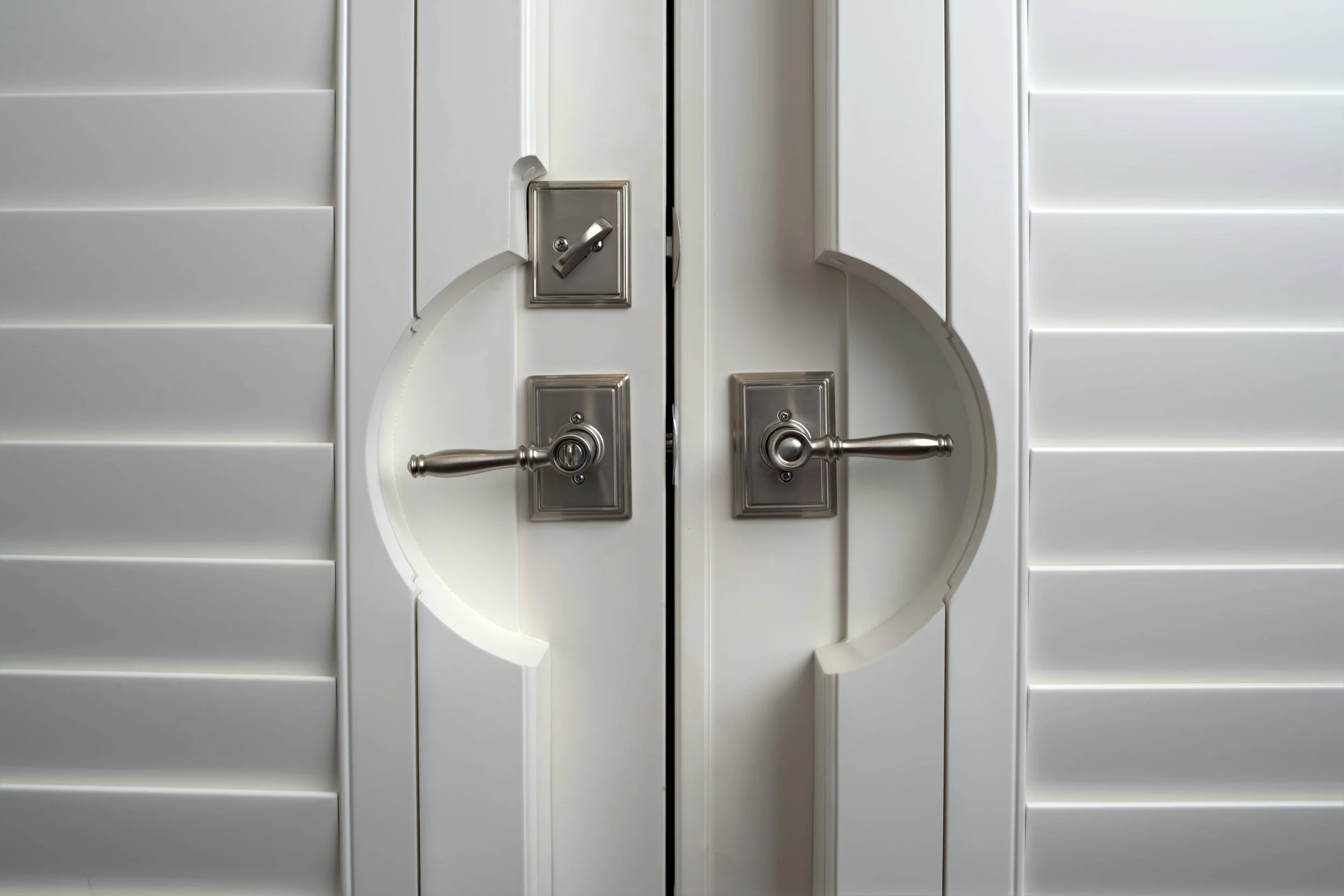 Close-up of a custom French door shutter cutout fitted around door handles in The Woodlands, Texas.