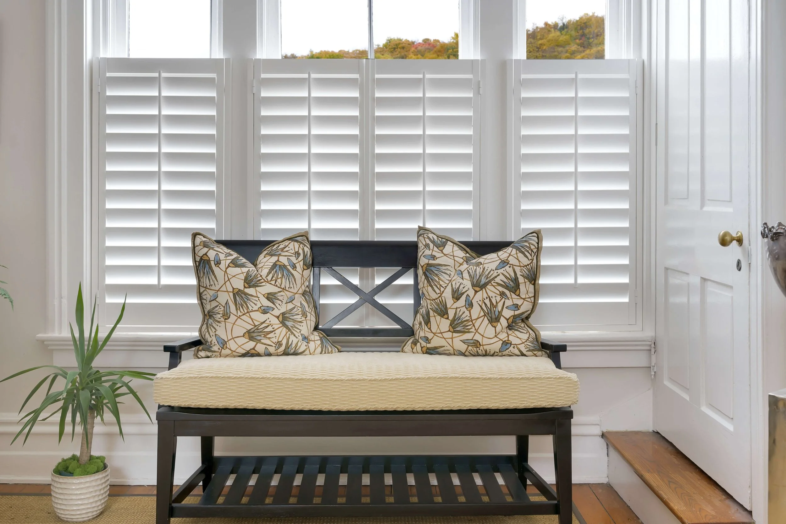 Close view of white café-style LiteLine shutters behind a window seat at Limewater Bistro.