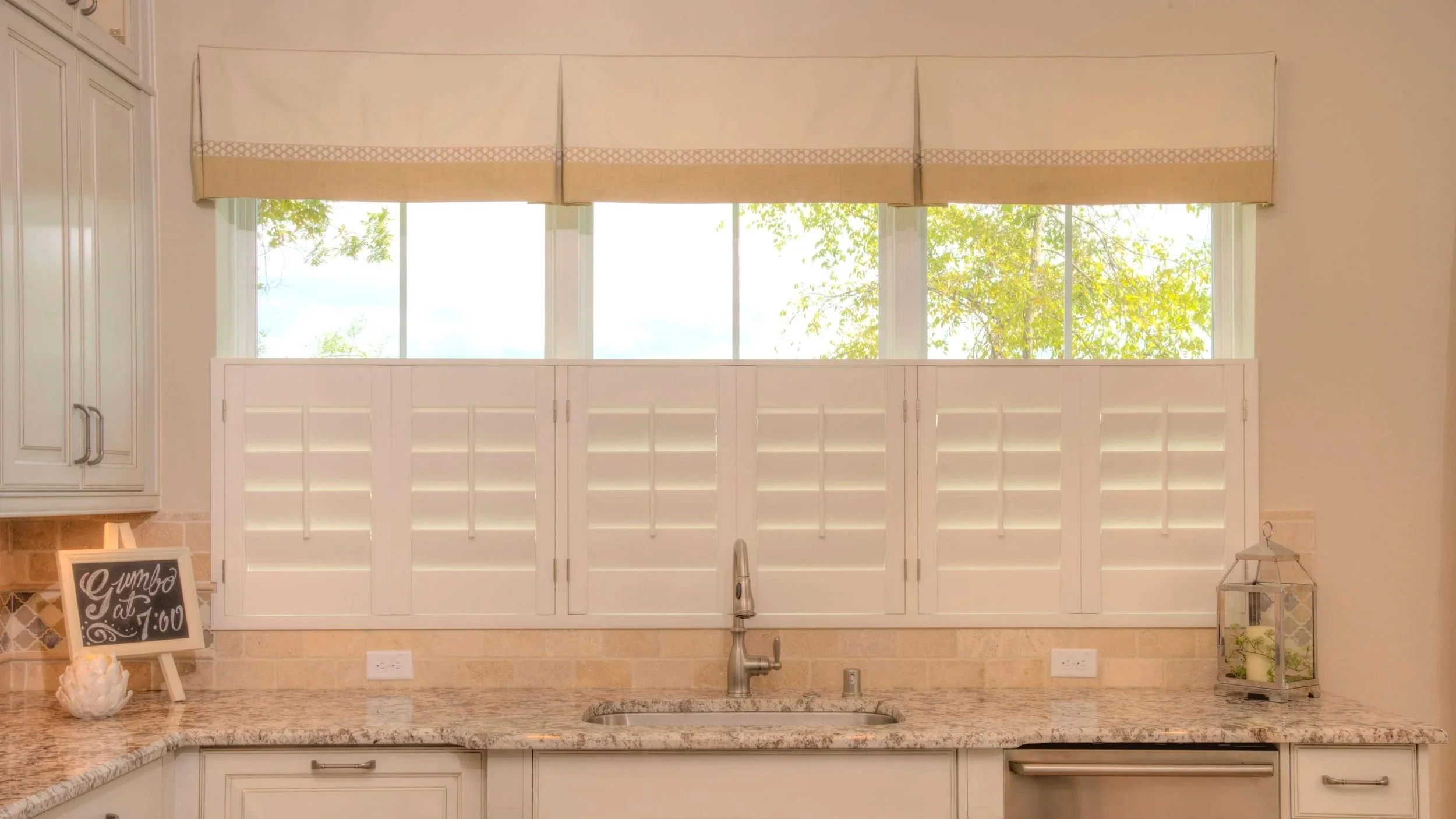 Cafe-style plantation shutters on a kitchen window in a River Oaks home in Houston, TX.