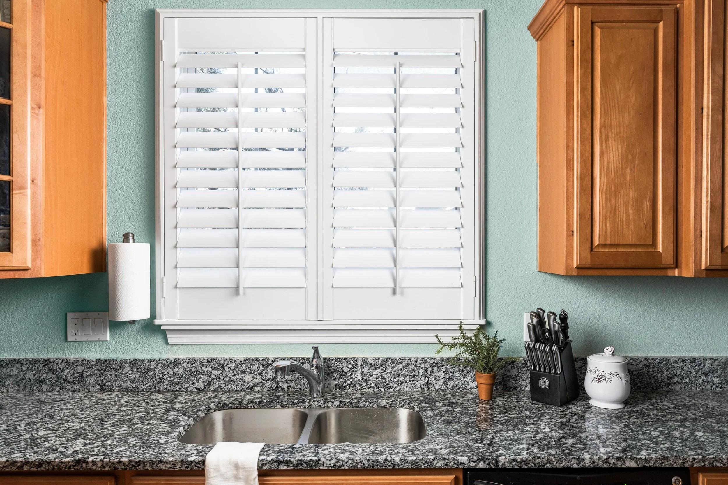 Bright white plantation shutters over kitchen sink in modern home in Colorado.