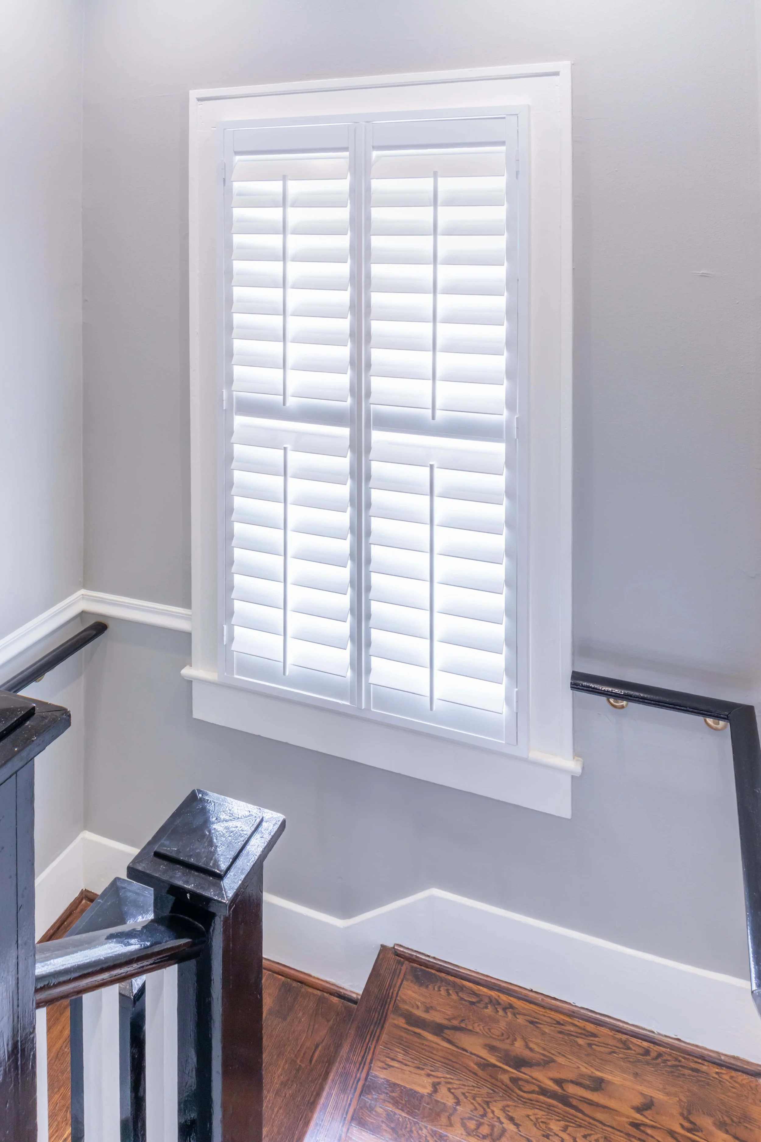 White plantation shutters on a stairway window in a Galveston beach house.