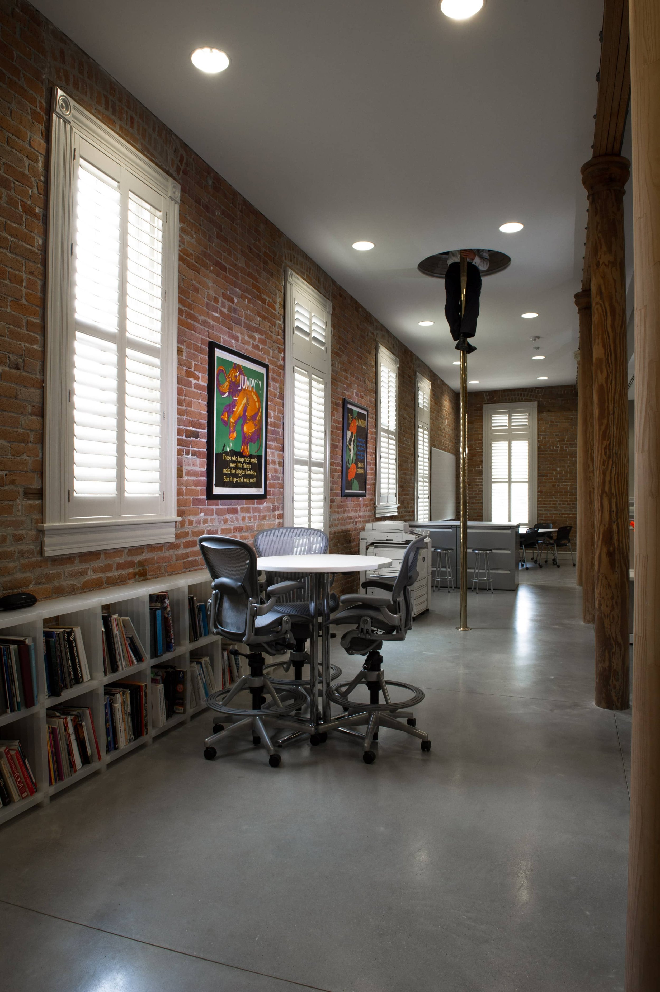 White custom shutters line the tall windows of a historic brick firehouse interior in St. Louis.