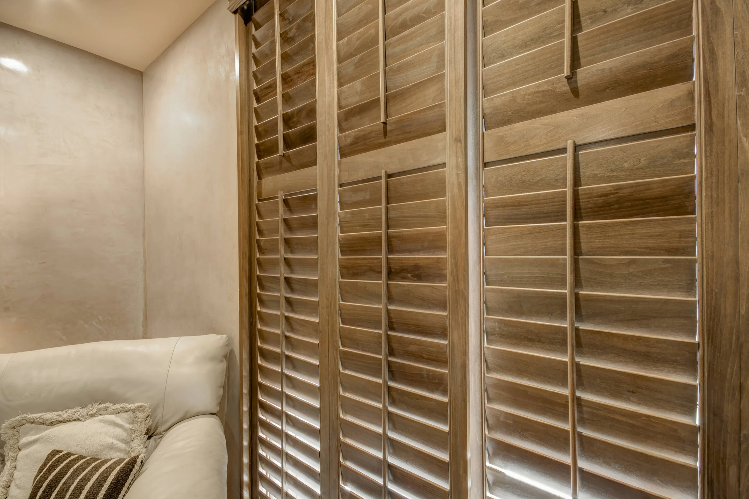 Close-up of Sands-stained hardwood shutters with divider rails and traditional tilt rods in a Santa Fe home.