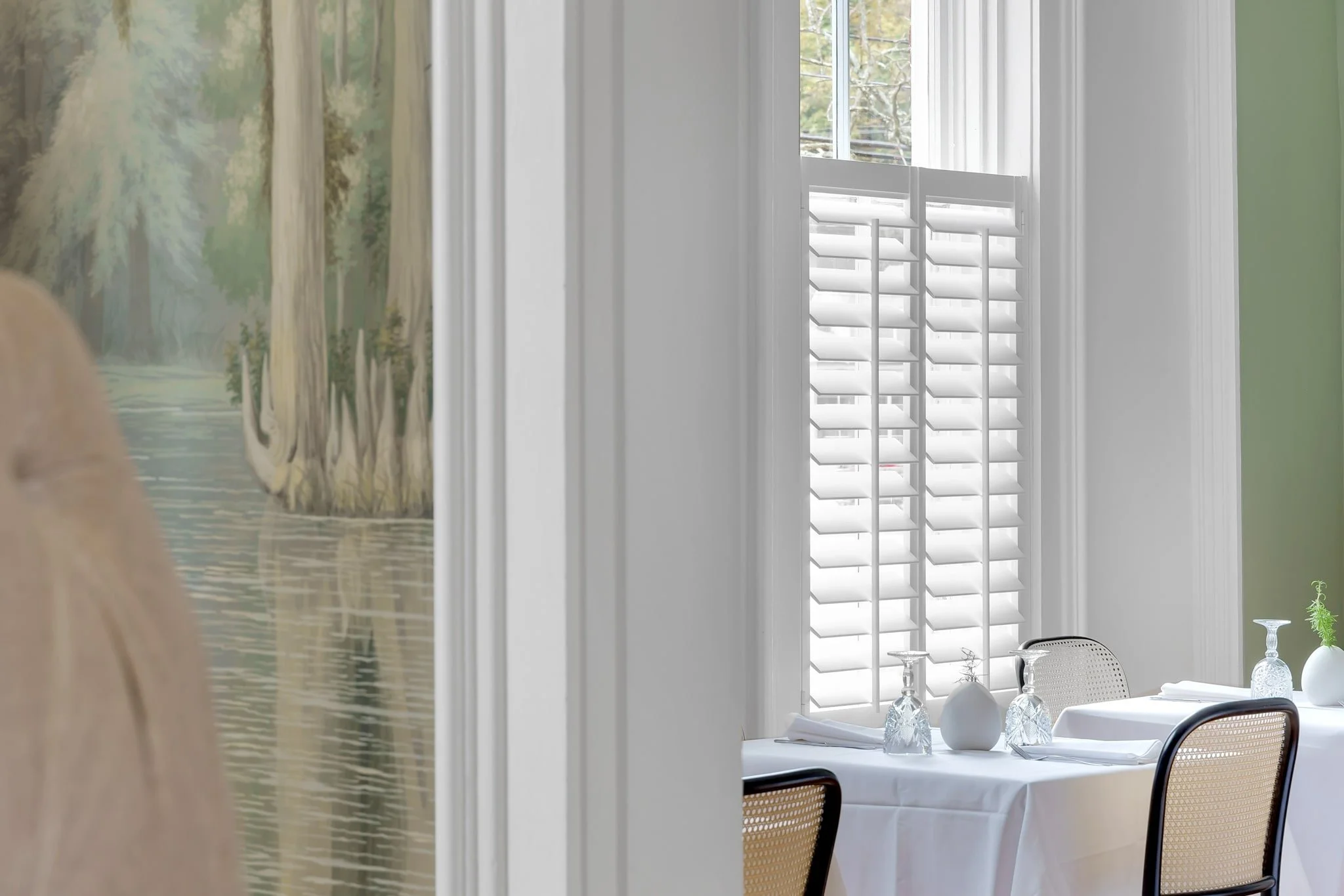 White café-style LiteLine shutters bring privacy and natural light to the dining room at Limewater Bistro.