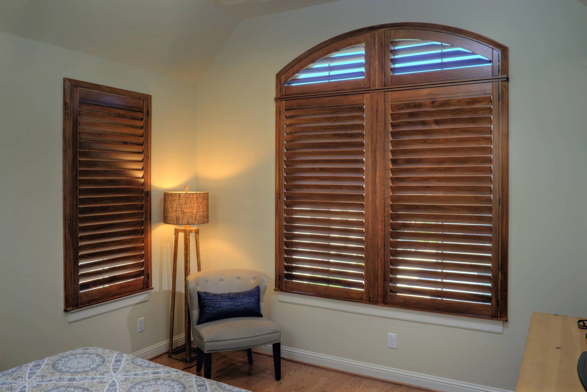 Terrace stained wood shutters with a custom arched transom in a The Woodlands, Texas bedroom.