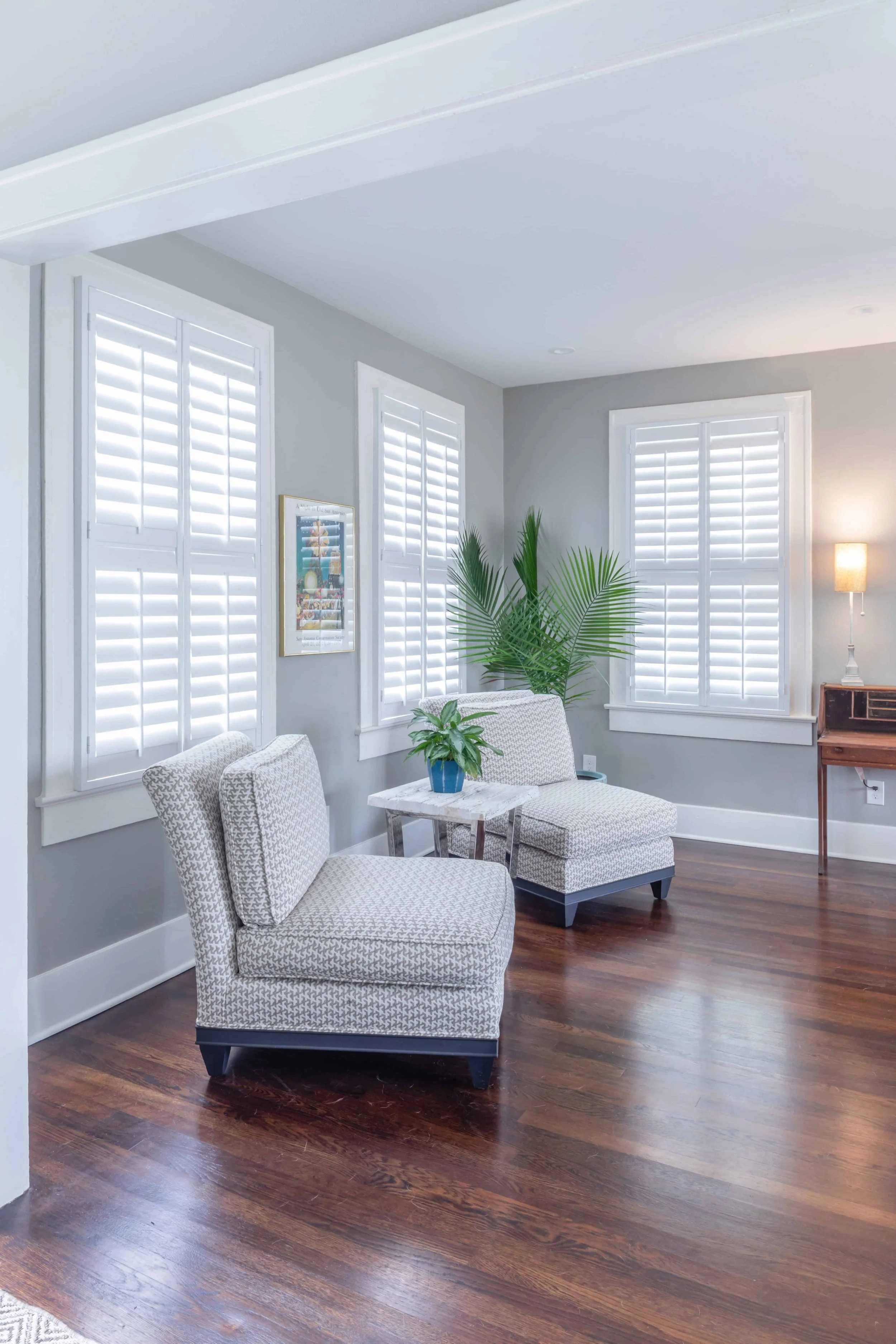 Bright sitting room with white plantation shutters and coastal furnishings in a Galveston home.