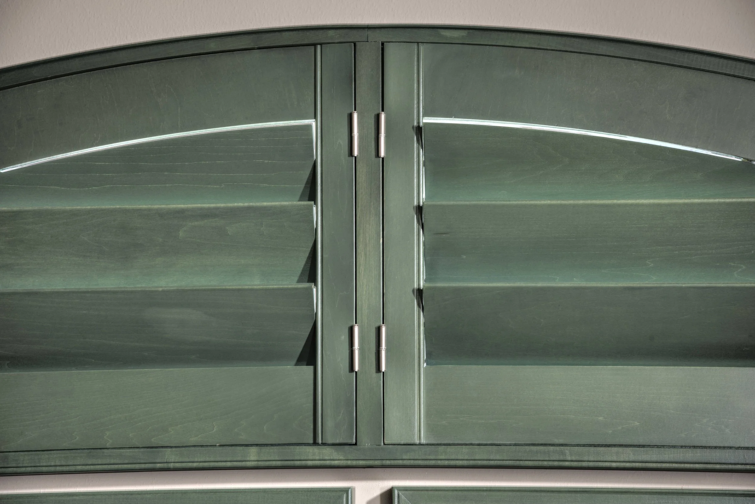 Detail of custom green stained arched shutters showing the wood grain and ClearLine tilt in a Chicago-area home.