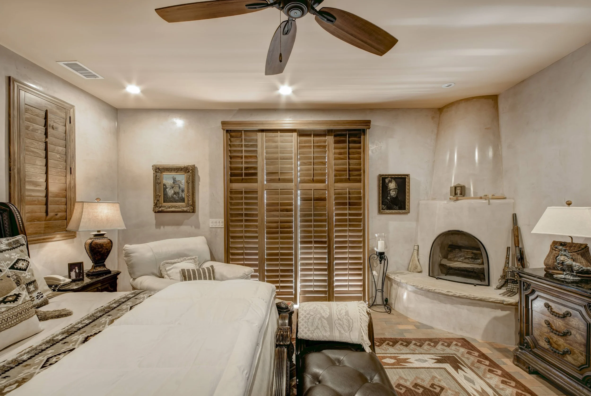 Santa Fe bedroom featuring Sands-stained hardwood shutters across a large sliding glass door.
