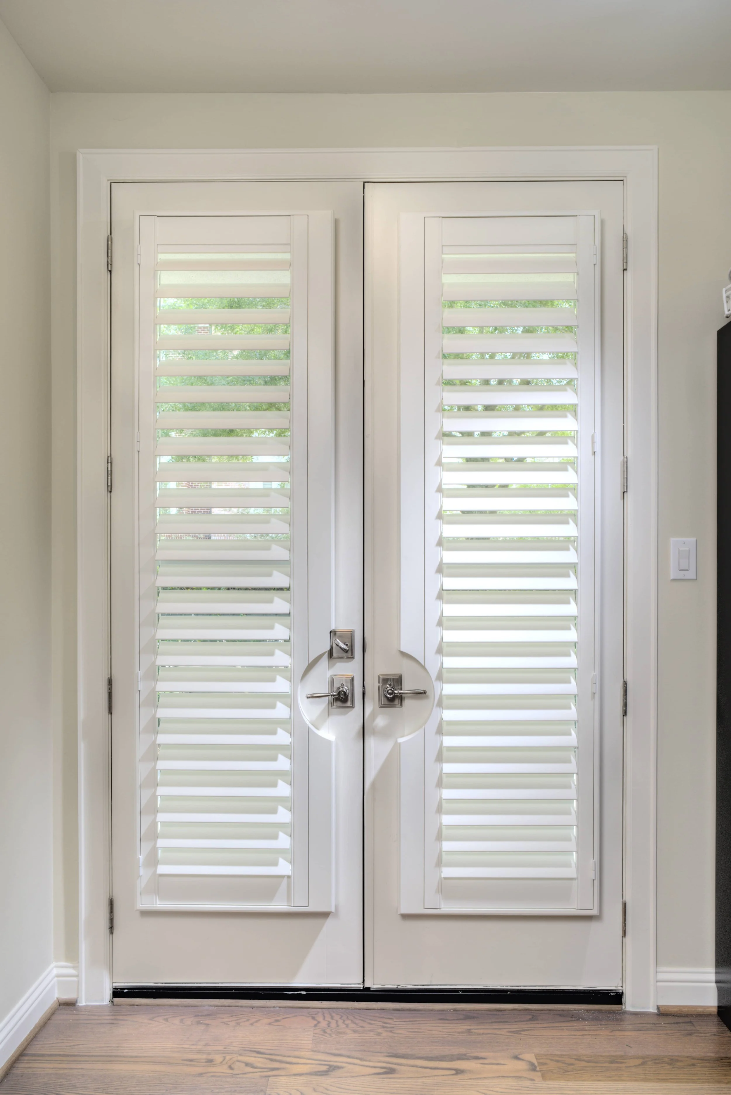 White French door shutters with custom handle cutouts in a The Woodlands, Texas home.