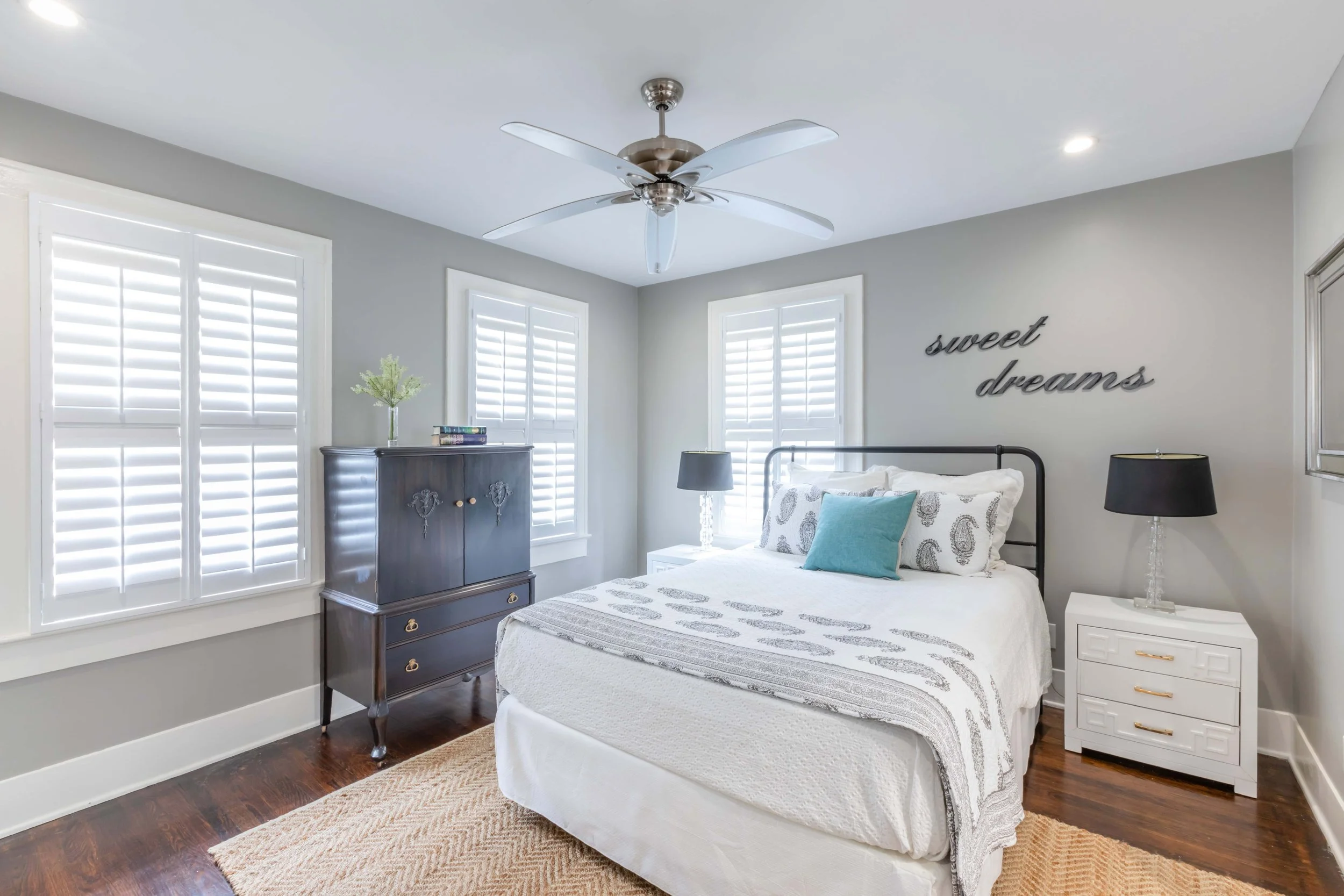 Galveston guest bedroom with white plantation shutters, hardwood floors and coastal blue accents.