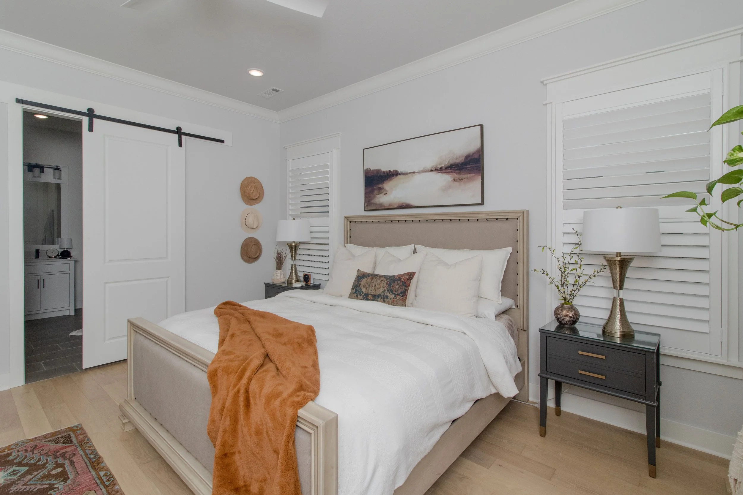 Primary bedroom in Northwest Arkansas with bright white Craftsman frame shutters flanking the bed.