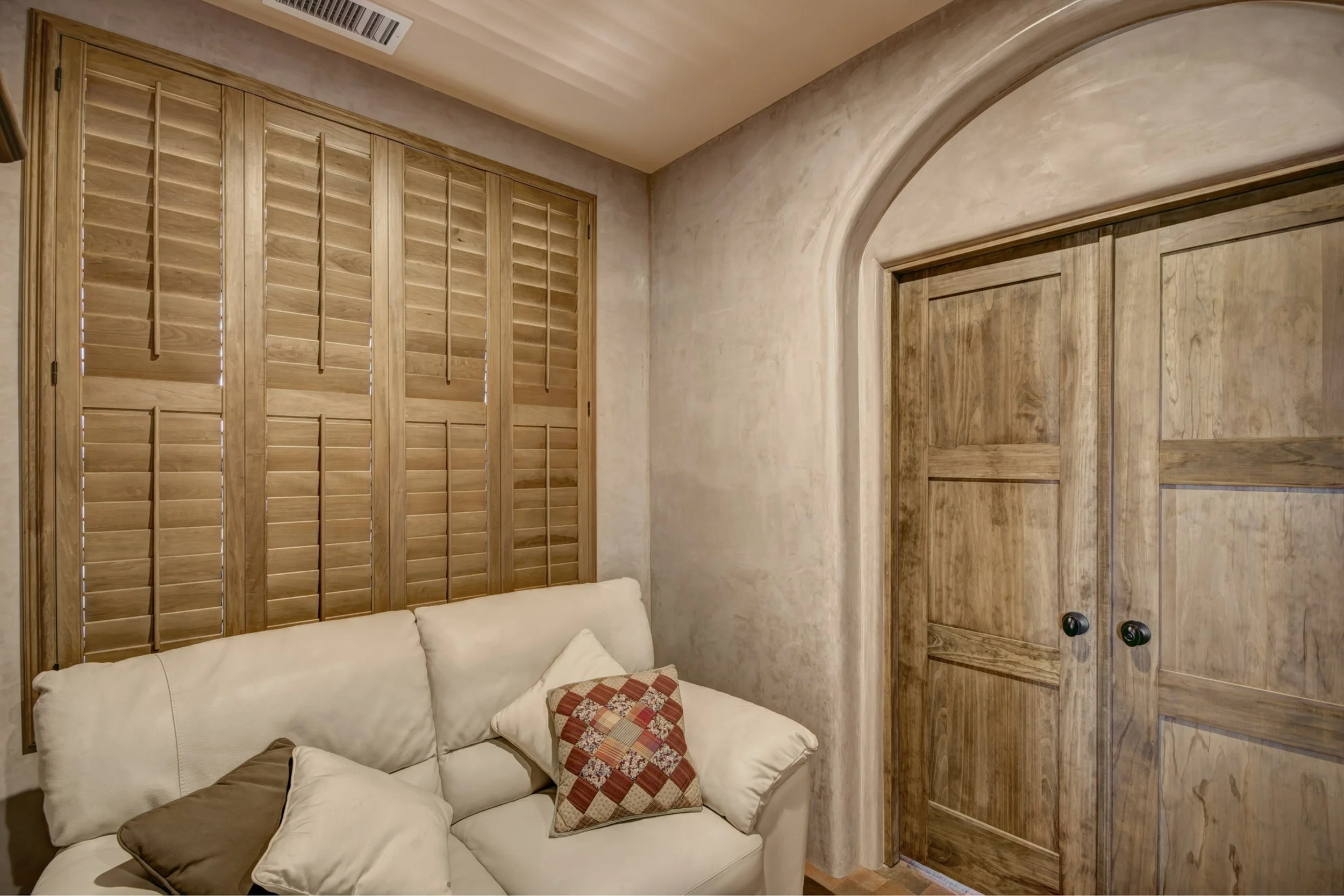 Sands-stained hardwood shutters complement plaster walls and rustic wood doors in a Santa Fe, New Mexico home.
