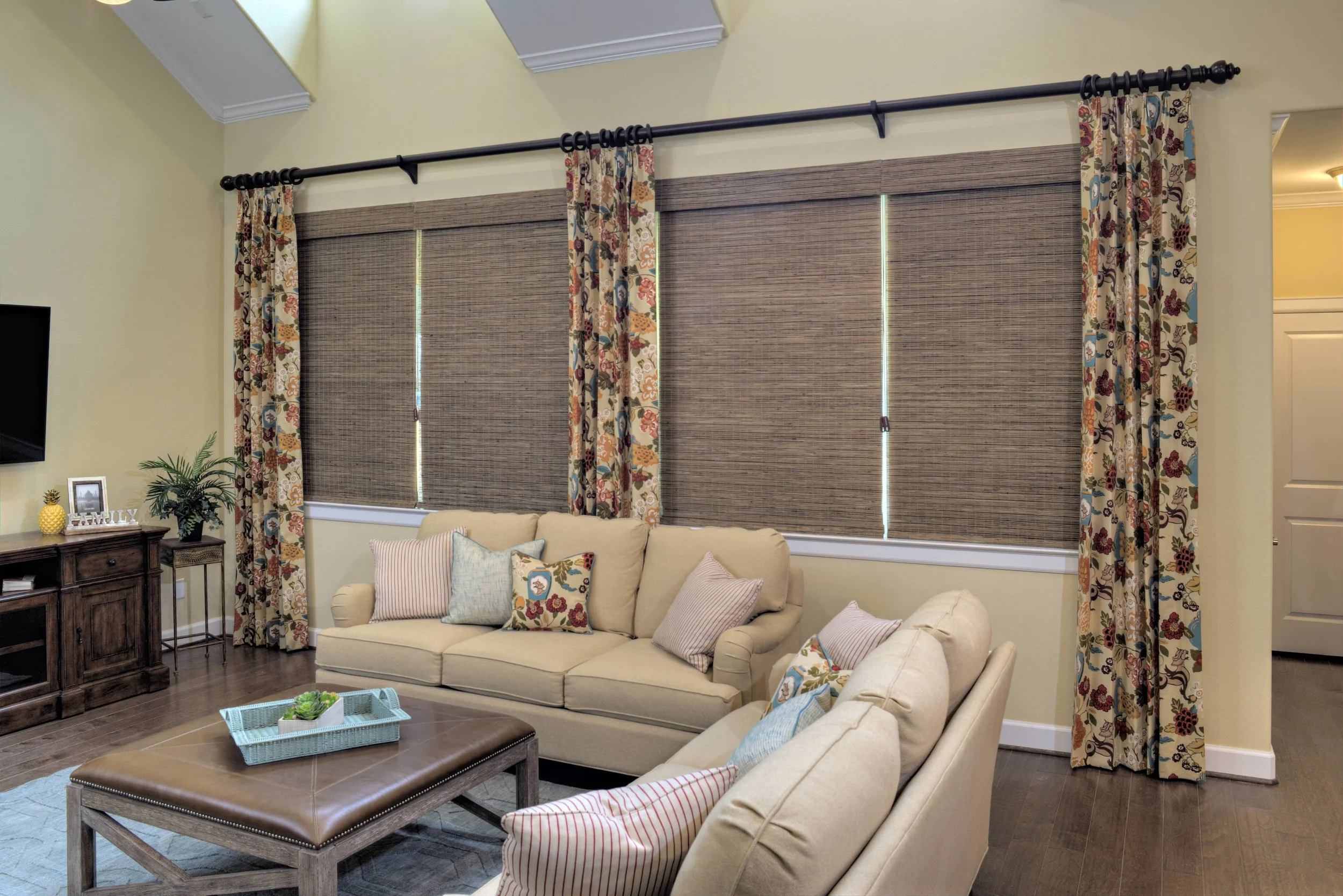 Woven wood shades layered with patterned drapery in the living room of a Houston, Texas home.