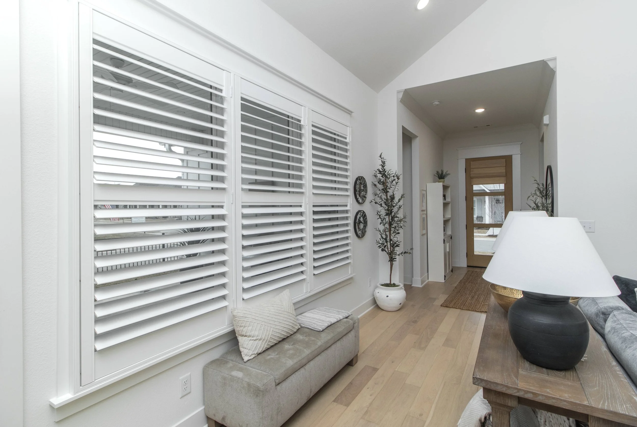 Bright white plantation shutters with 3.5-inch louvers across living room windows in Northwest Arkansas.
