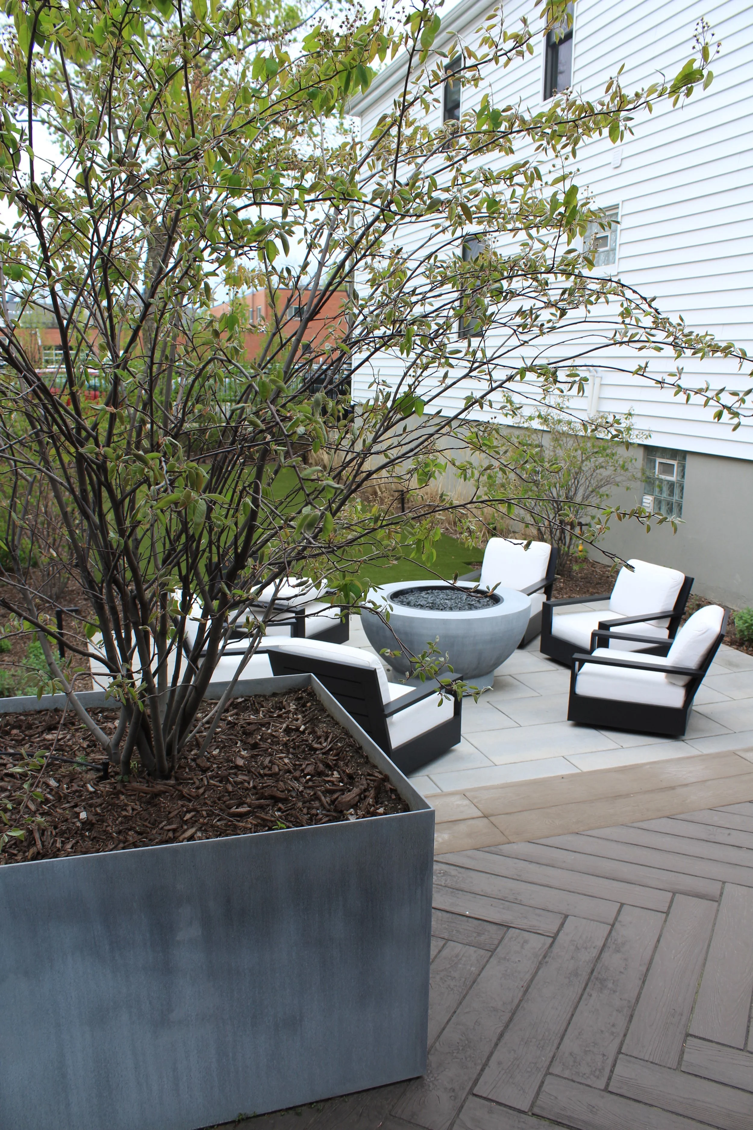 This custom space embraced two levels of patio and yard space, a custom louvered aluminum pergola complete with heater, lights, and fans, an outdoor fire pit, synthetic turf lawn for the pups and kids to play on, custom lighting system, and irrigatio