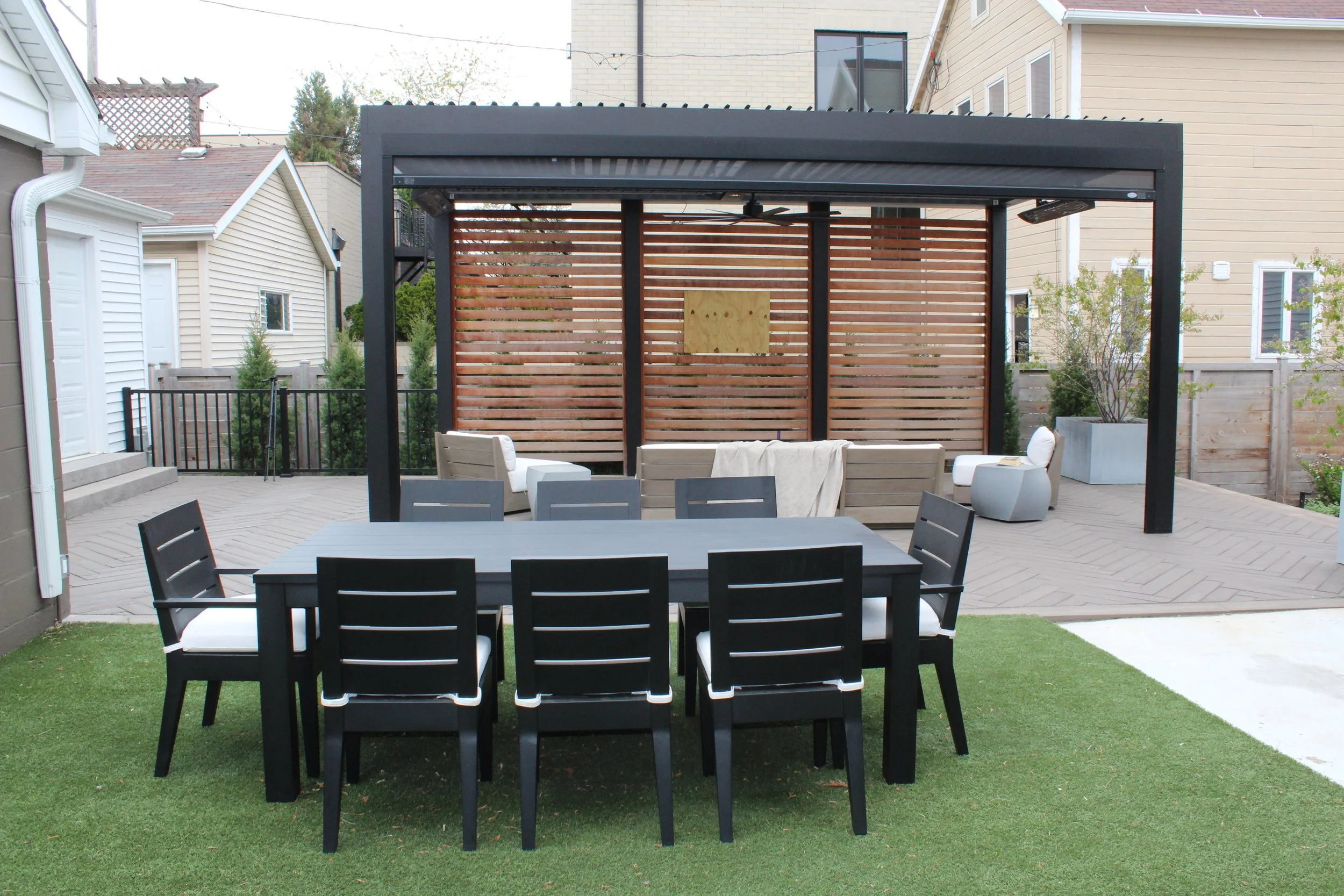 This custom space embraced two levels of patio and yard space, a custom louvered aluminum pergola complete with heater, lights, and fans, an outdoor fire pit, synthetic turf lawn for the pups and kids to play on, custom lighting system, and irrigatio
