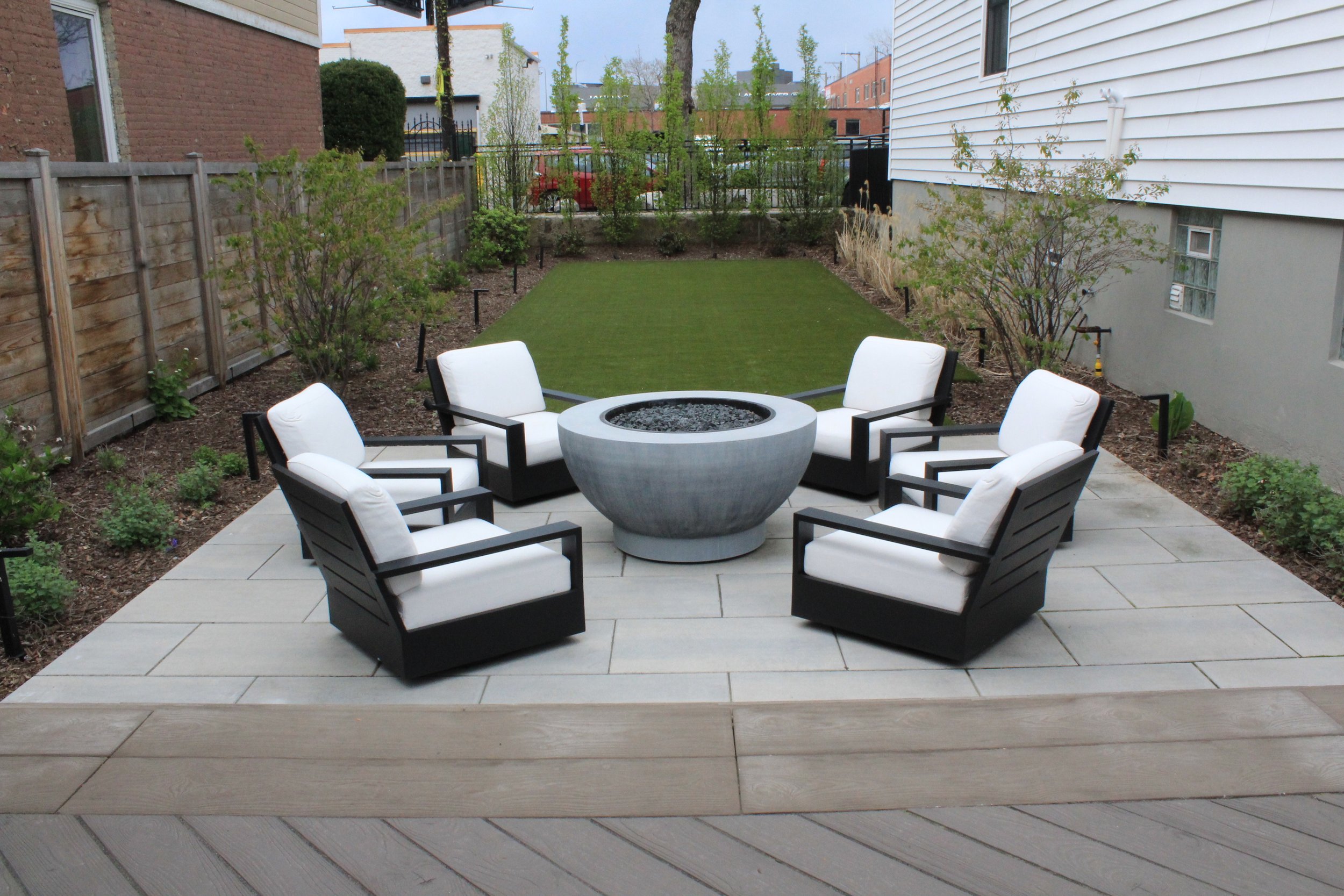 This custom space embraced two levels of patio and yard space, a custom louvered aluminum pergola complete with heater, lights, and fans, an outdoor fire pit, synthetic turf lawn for the pups and kids to play on, custom lighting system, and irrigatio