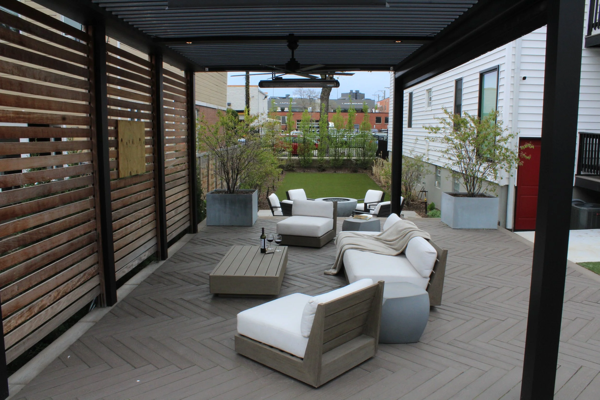 This custom space embraced two levels of patio and yard space, a custom louvered aluminum pergola complete with heater, lights, and fans, an outdoor fire pit, synthetic turf lawn for the pups and kids to play on, custom lighting system, and irrigatio