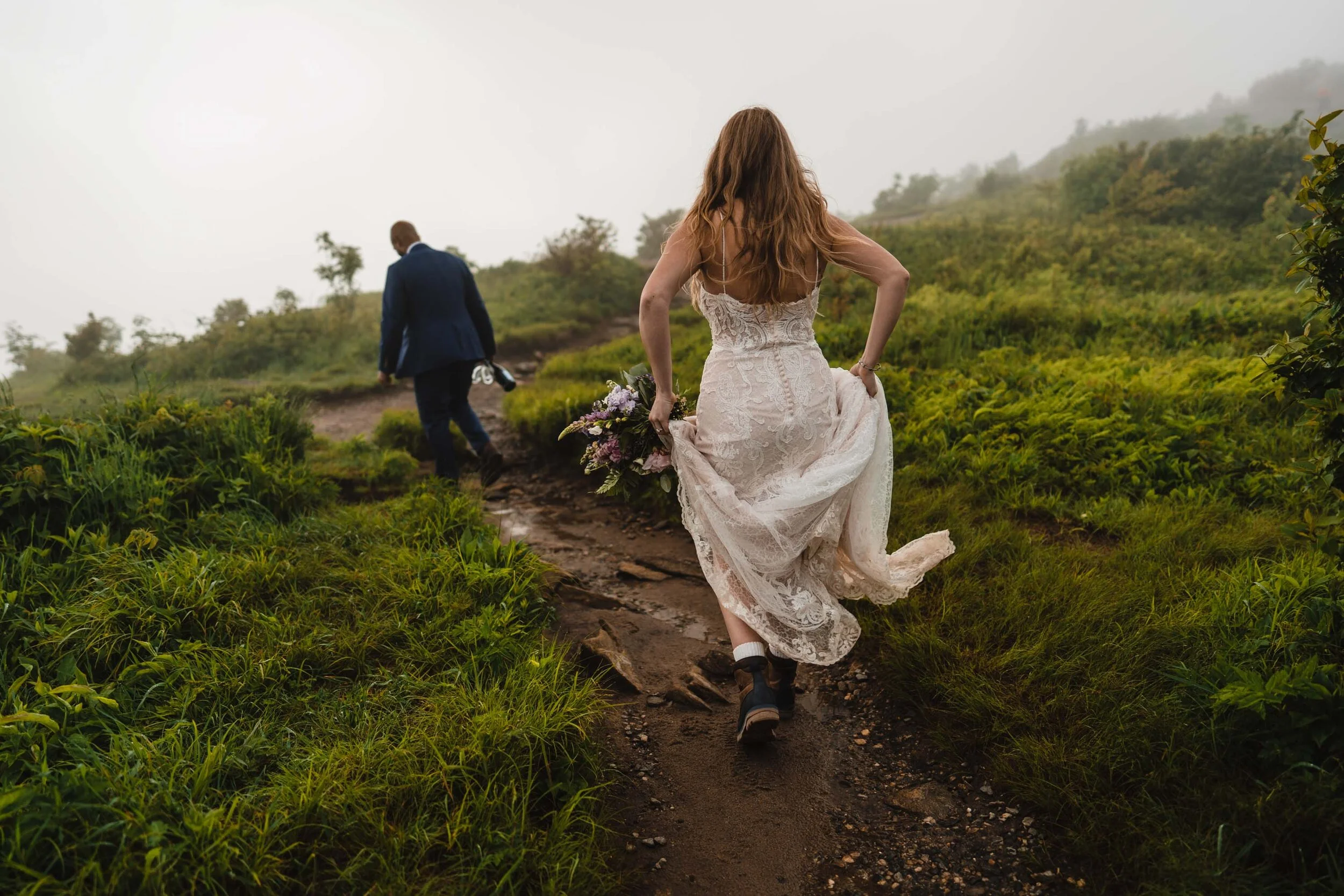 Bride hiking a foggy mountain trail in her wedding dress and hiking shoes