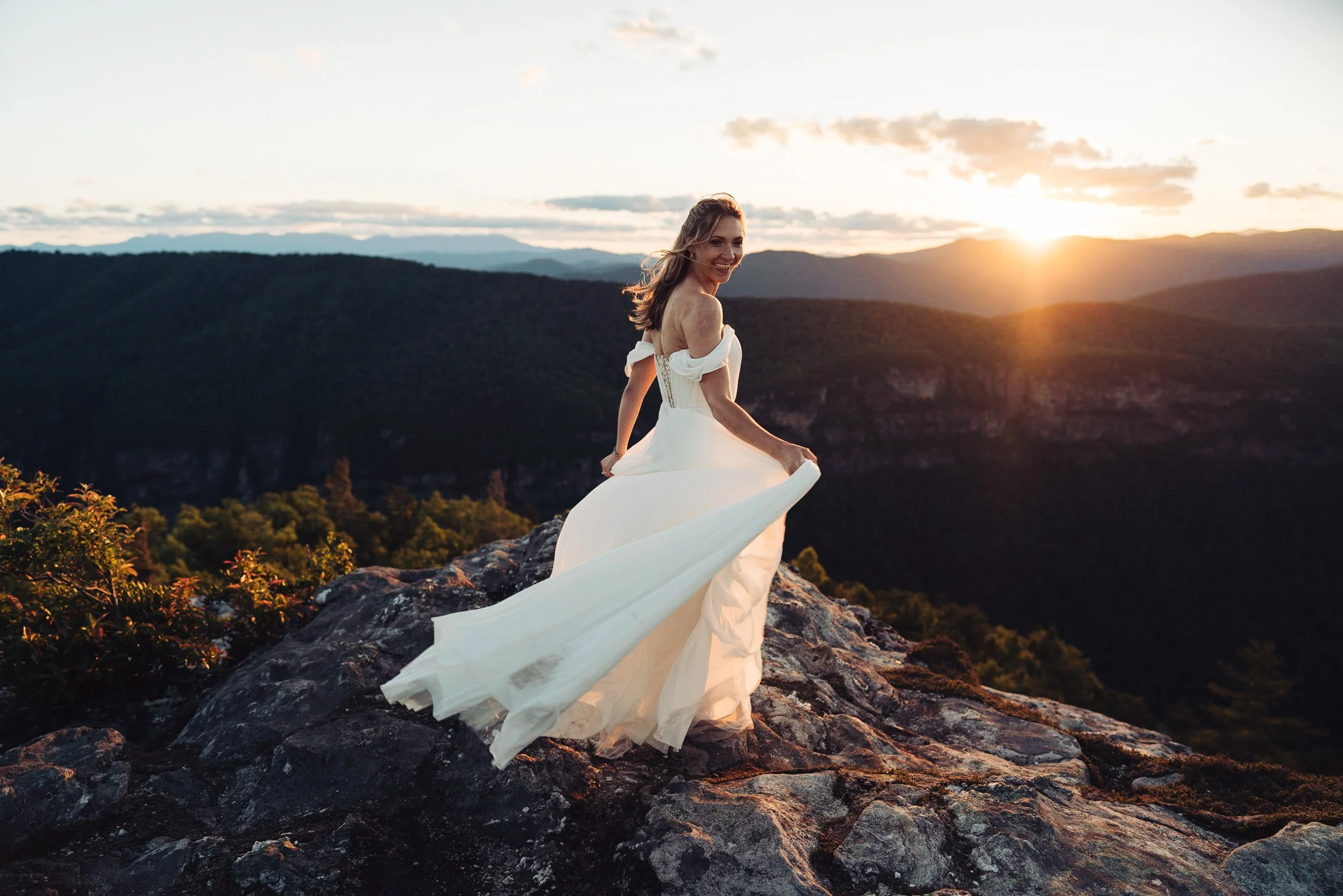 Kaitlyn twirling in her wedding dress on a rocky Linville Gorge overlook at sunset