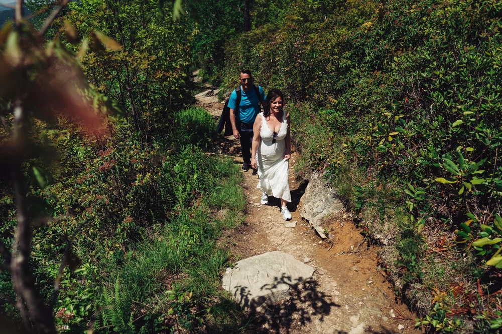 Andrea and Adam hiking along a rocky mountain trail on their elopement day