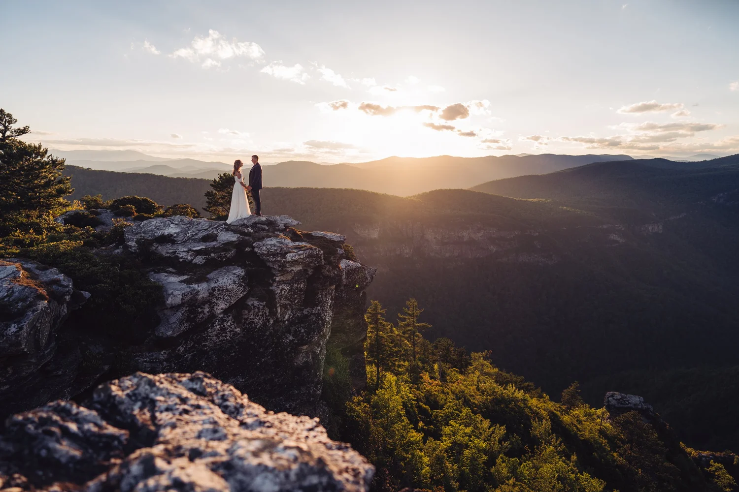 Kaitlyn and Evan standing together on a cliff overlooking Linville Gorge at sunset